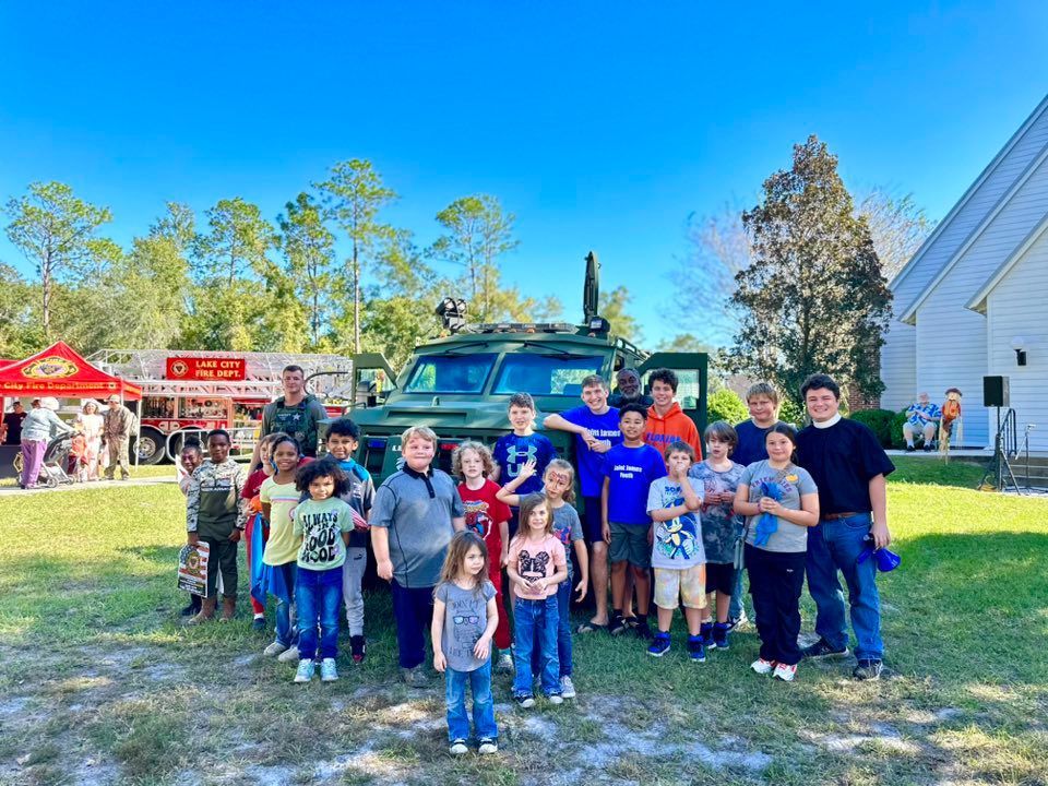 The church youth stand in front of a police combat vehicle with Fr. William in front of St. James church