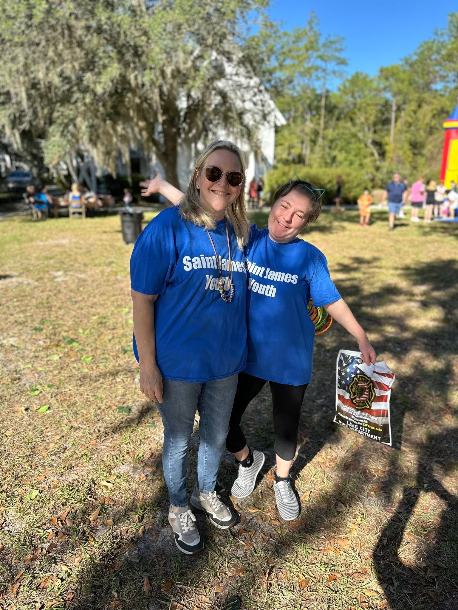 The Youth Director and a Youth Group member stand outside in front of the Historic Chapel wearing blue youth shirts.