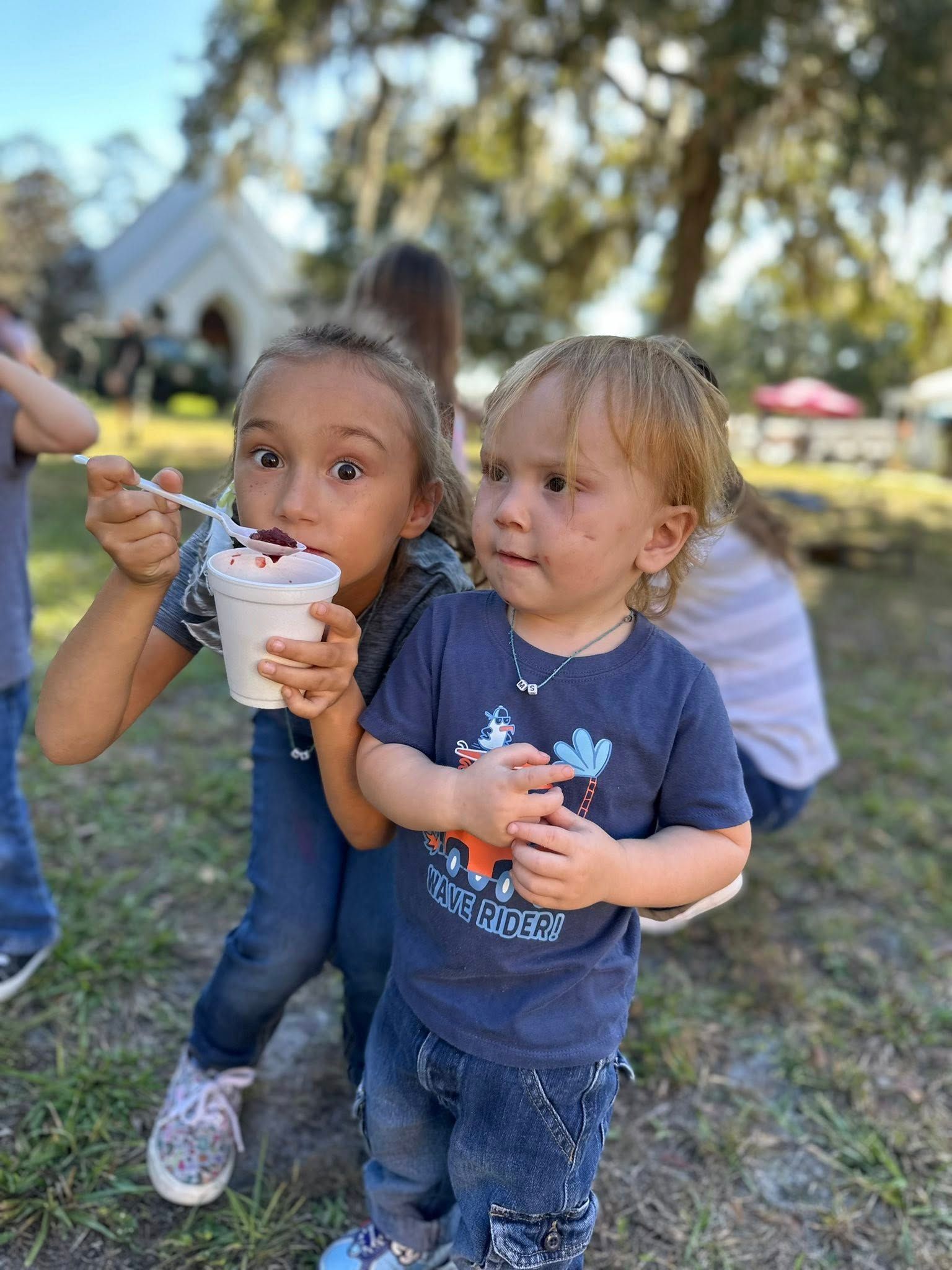 Two children enjoy ice cream with St. James Episcopal Church in the background