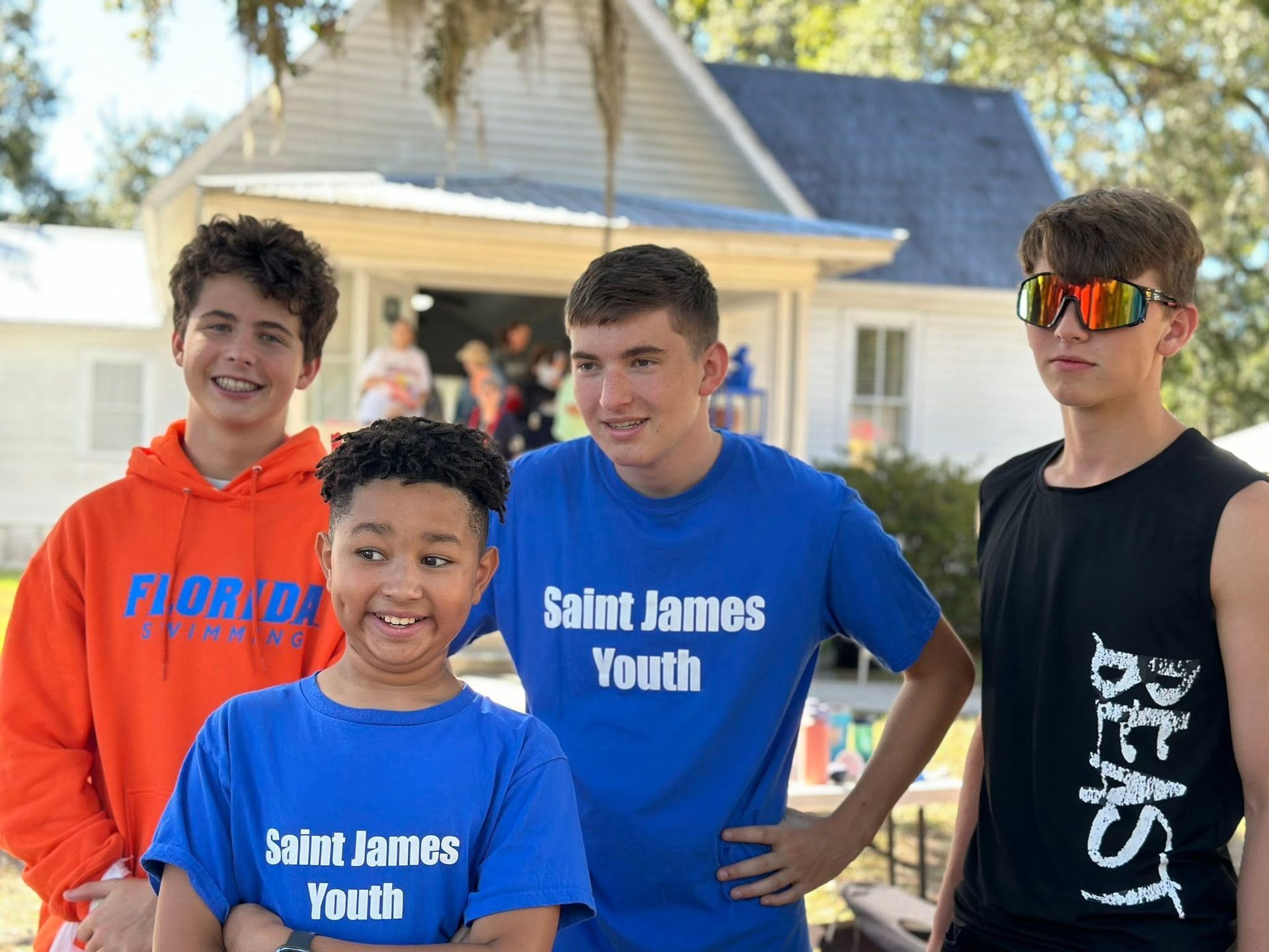 A group of youths stand in front of St. James Parish Hall with various expressions