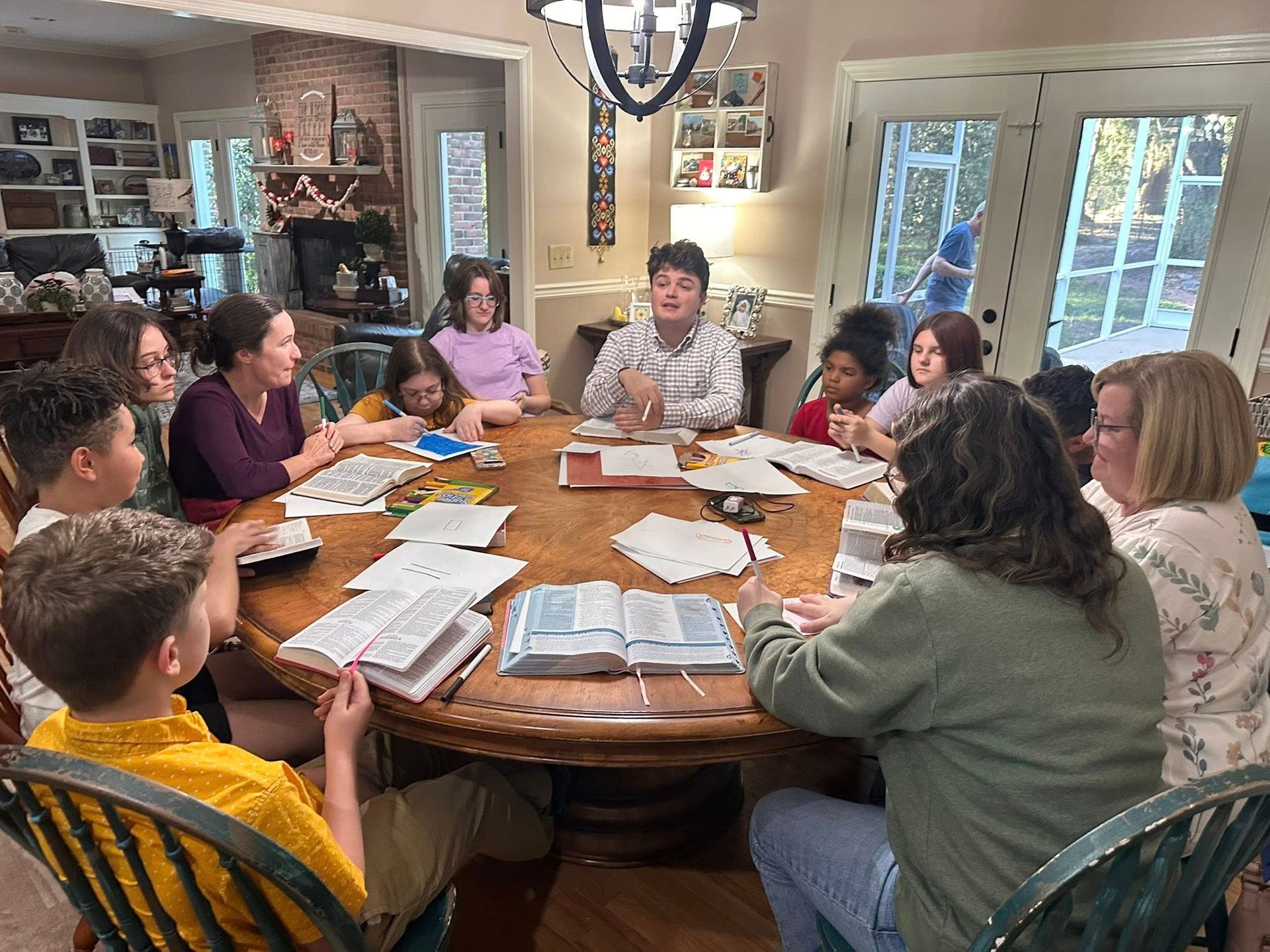A study group surrounding a table with Fr. William at center discussing a topic