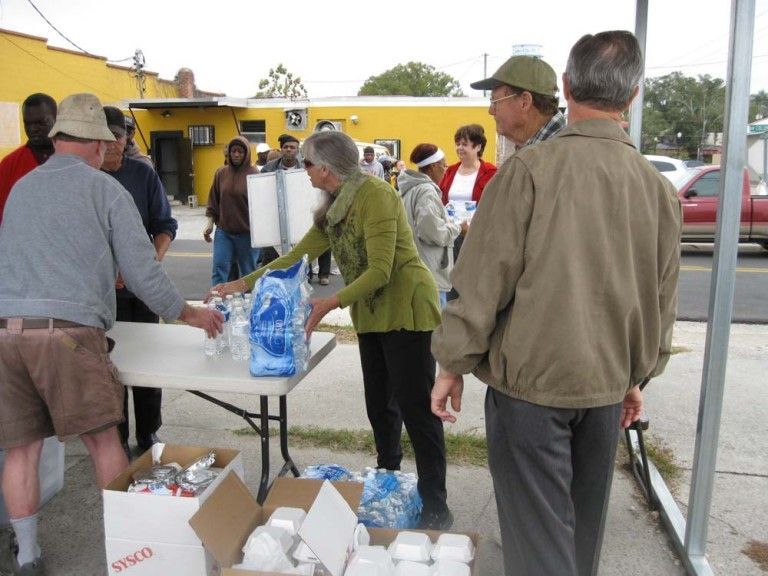 Volunteers distribute supplies on a tabletop underneath a tent outside