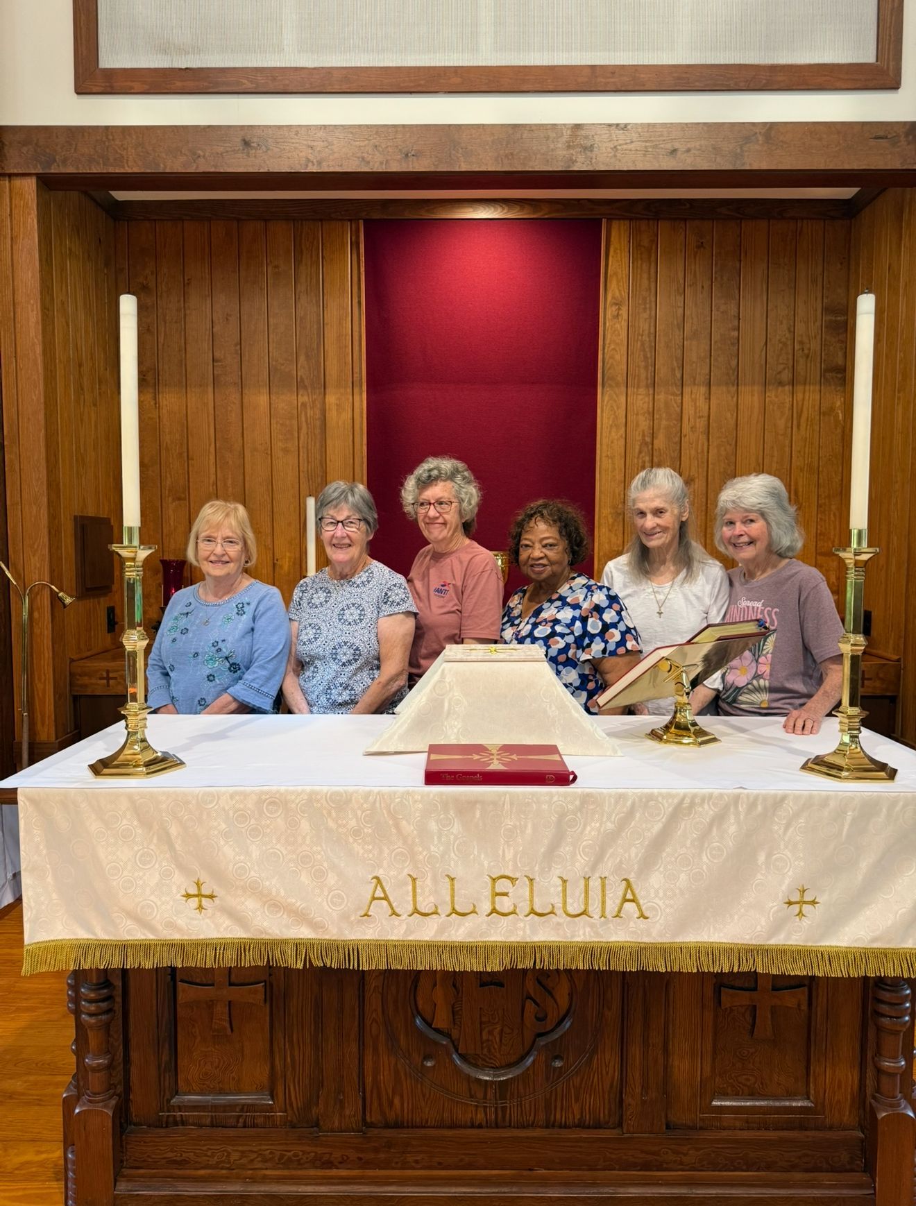 A group of women standing in front of a decorated altar inside the Sanctuary at St. James Episcopal Church