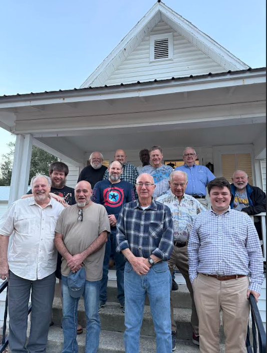 A group of men stand in front of the porch of Parish Hall