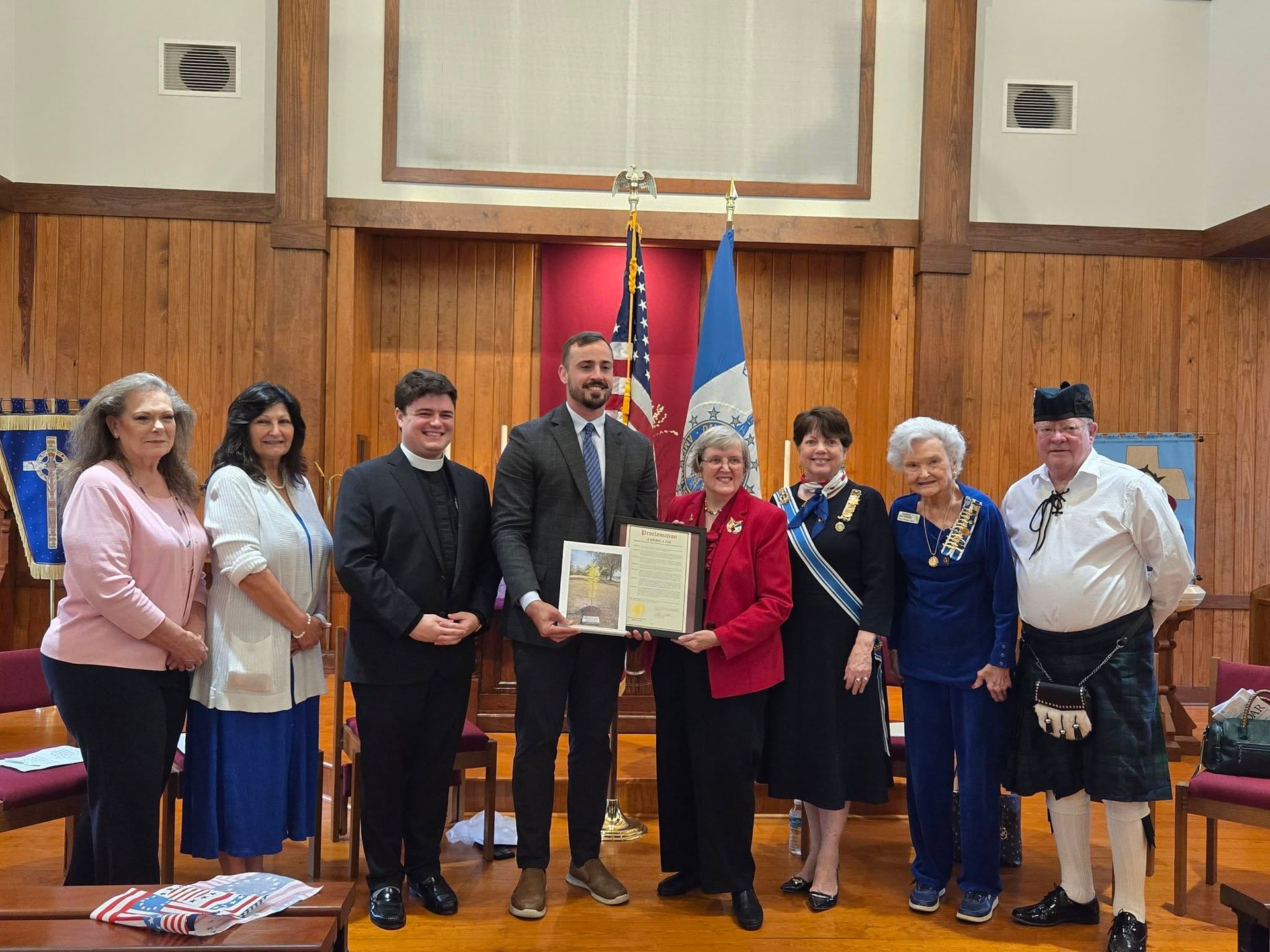 A group of dignitaries stands holding plaques with church and community leaders.