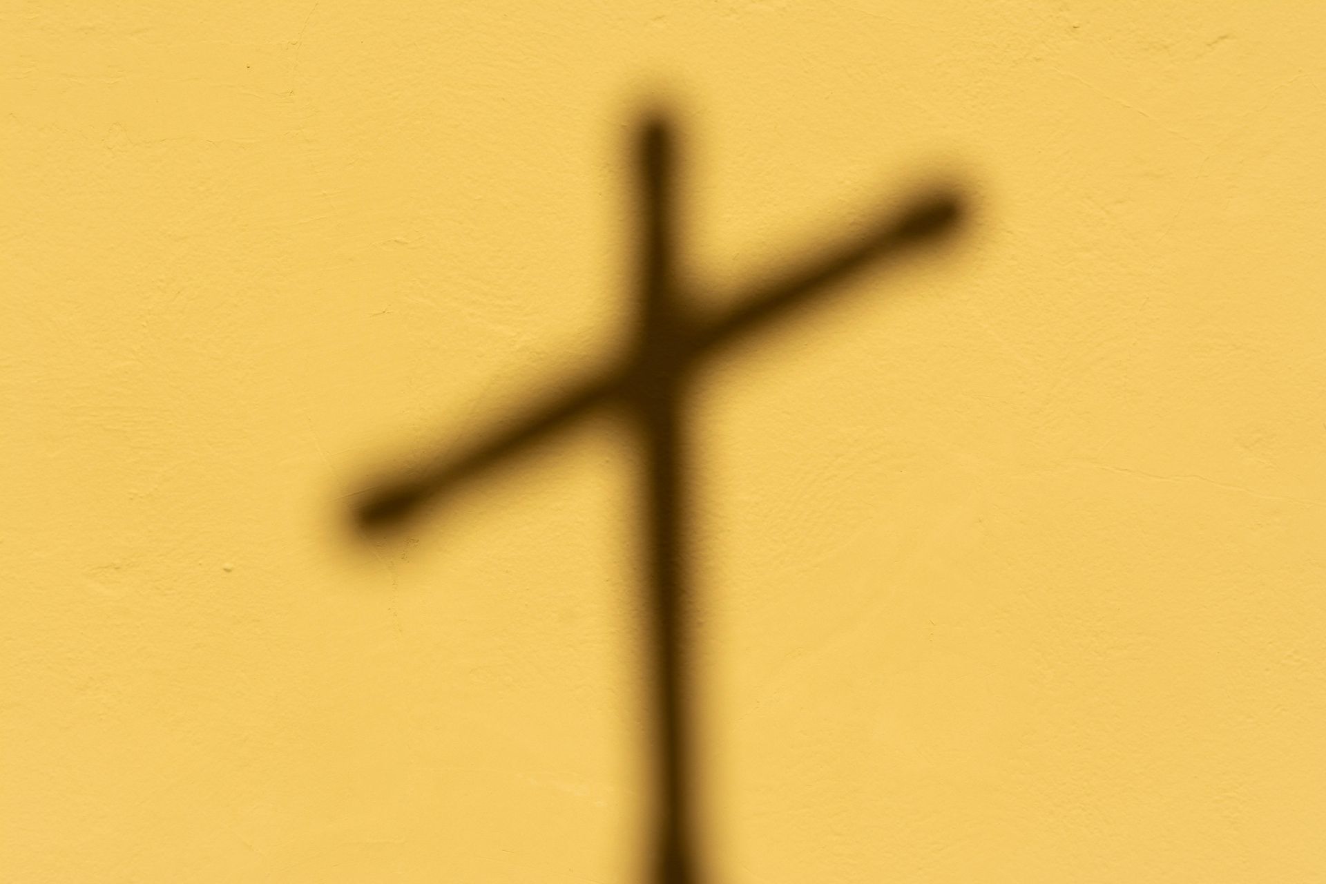 A yellow background with a cross shadow at center