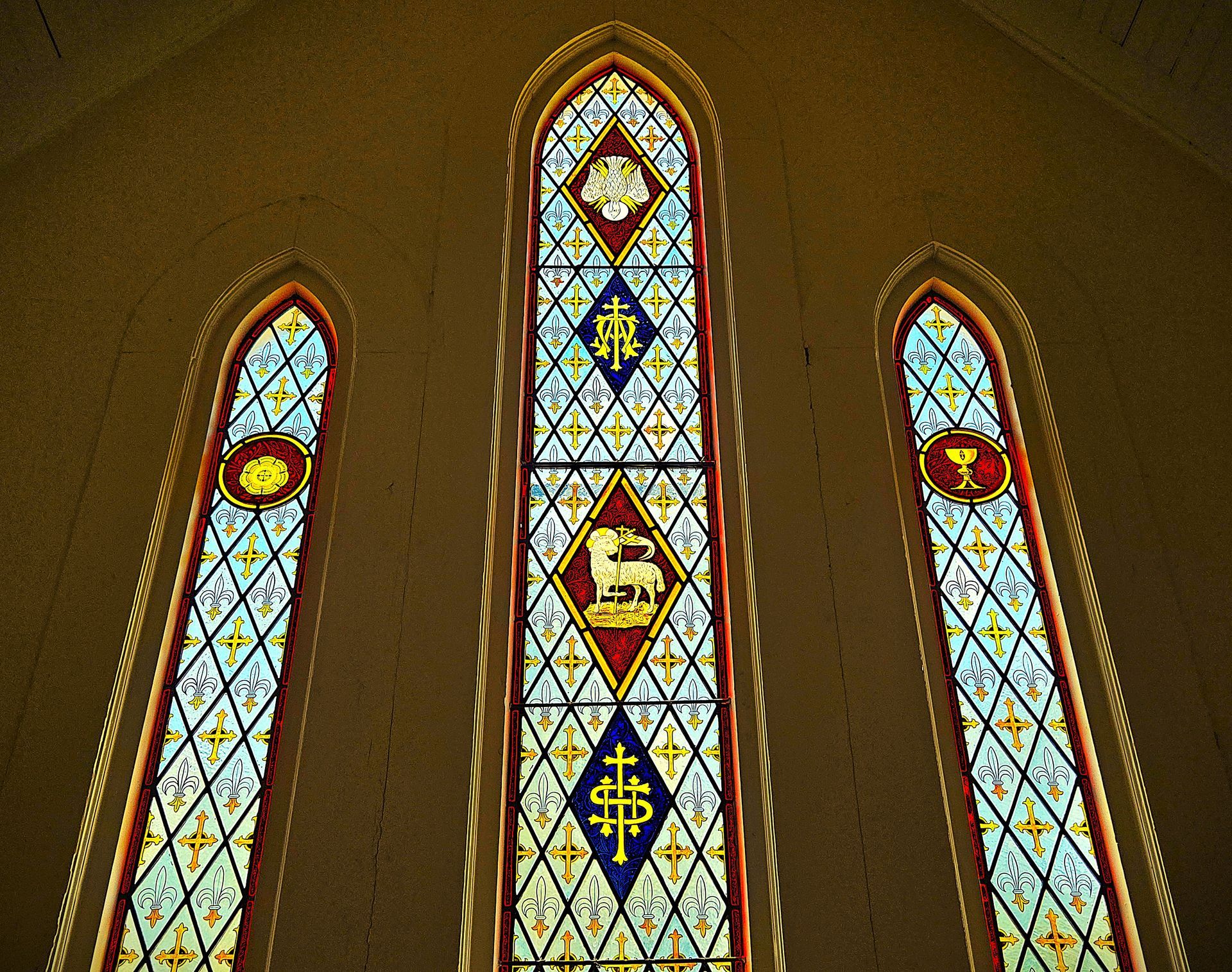 Intricate patterns of Christian iconography adorning lit stained glass windows of St. James Episcopal Church Historic Chapel
