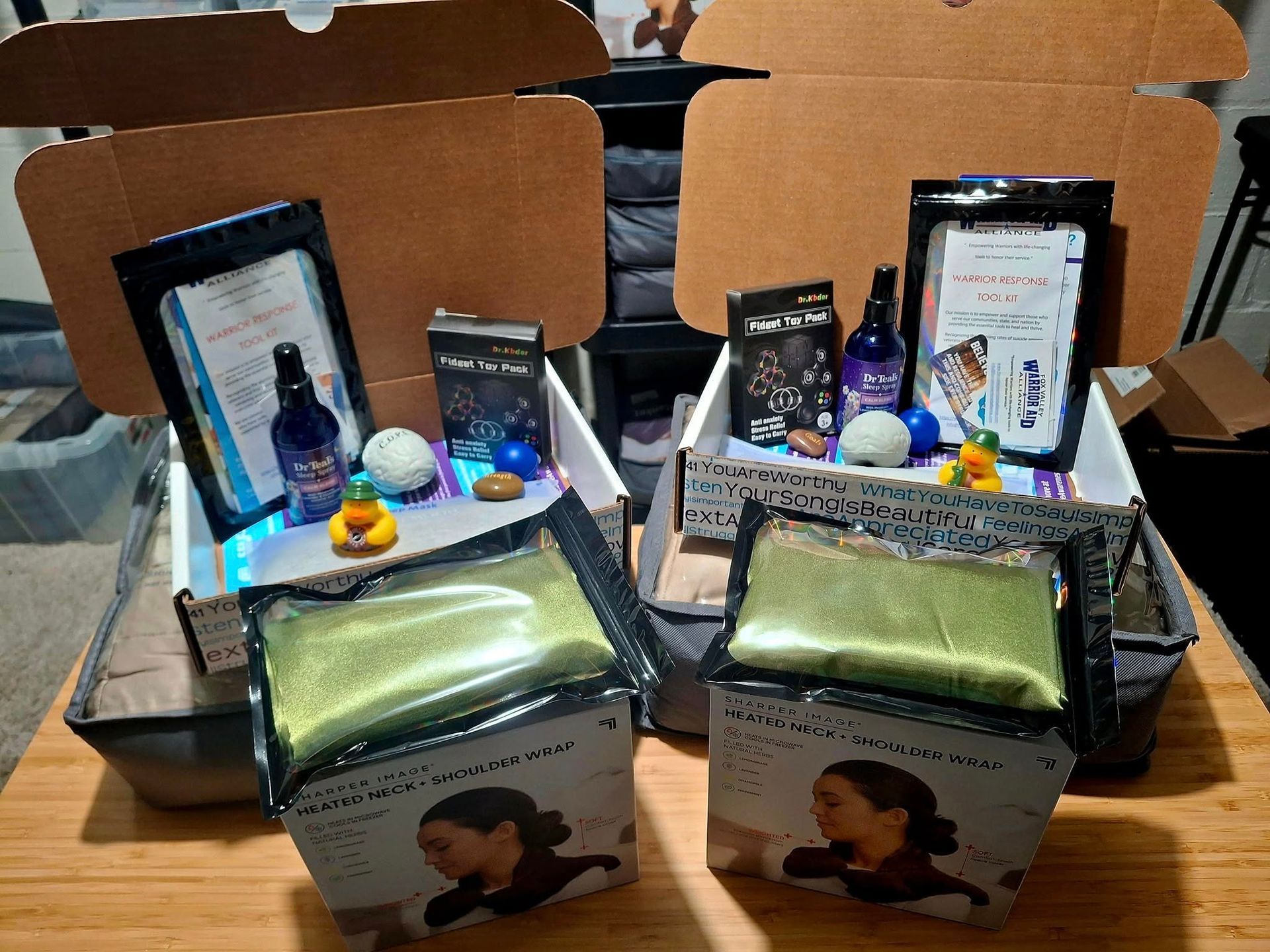 Two open boxes with various beauty products: bags of powder, bottles, balls, and a rubber duck.