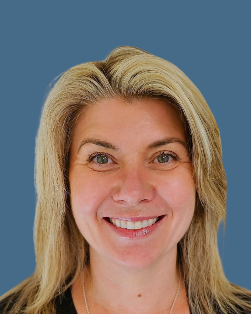 A smiling person with shoulder-length blonde hair, centered against a solid blue background.