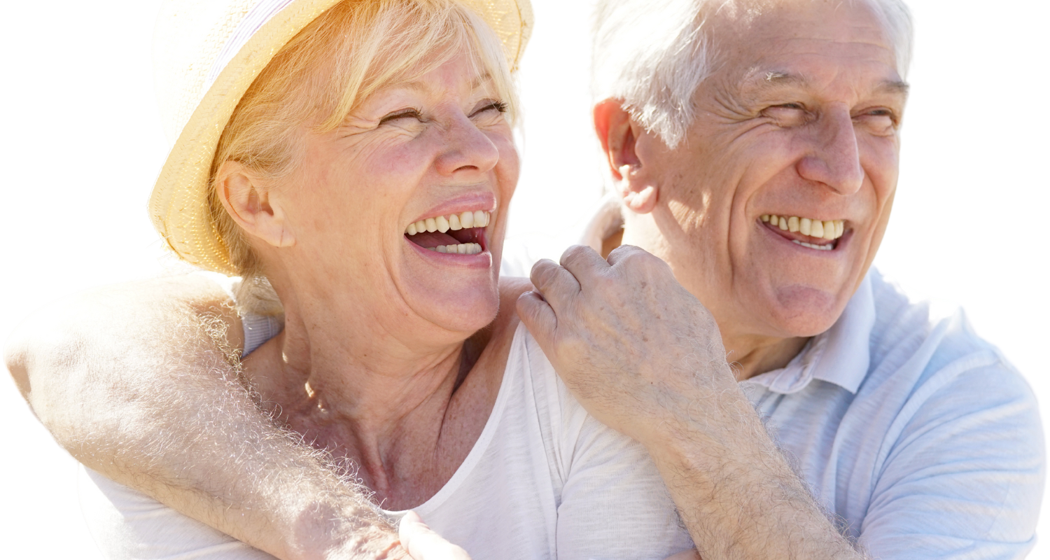 A couple wearing casual clothing embraces while laughing outdoors against a bright, sun-drenched background.