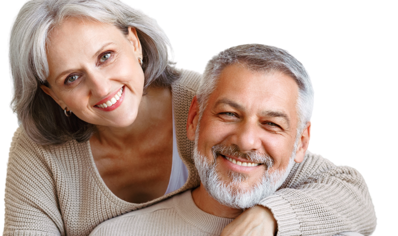 A smiling pair dressed in beige knit sweaters poses together against a plain white background.