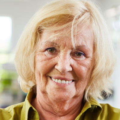 A smiling individual with blonde hair wearing a green collared shirt, shown in a close-up headshot.