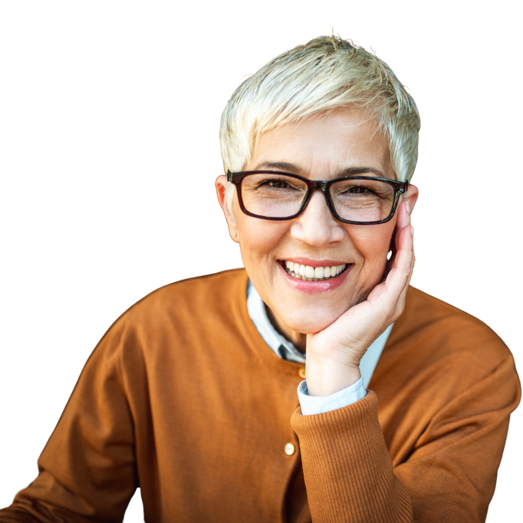 A person with short, blonde hair and glasses smiles while resting their chin on their hand, wearing a tan cardigan.