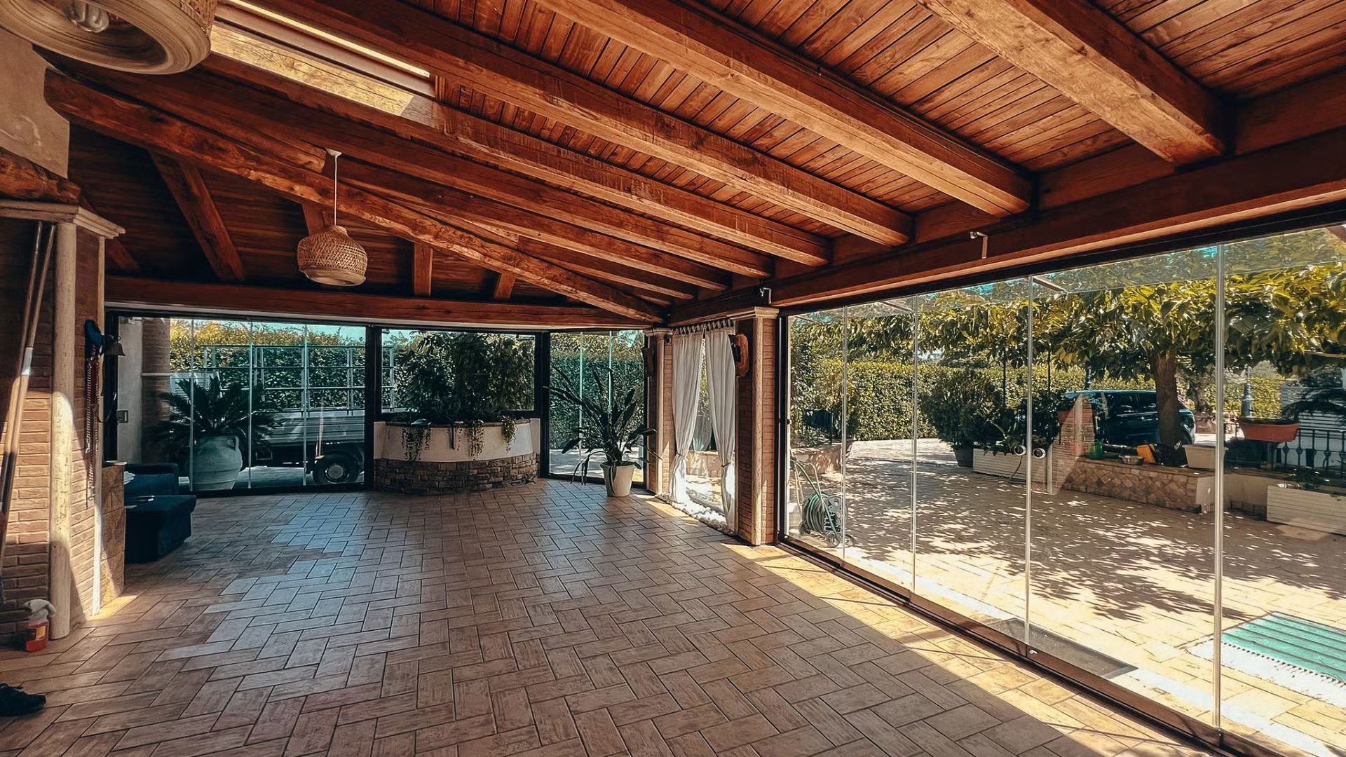 Una stanza vuota con un soffitto in legno e una piscina sullo sfondo.