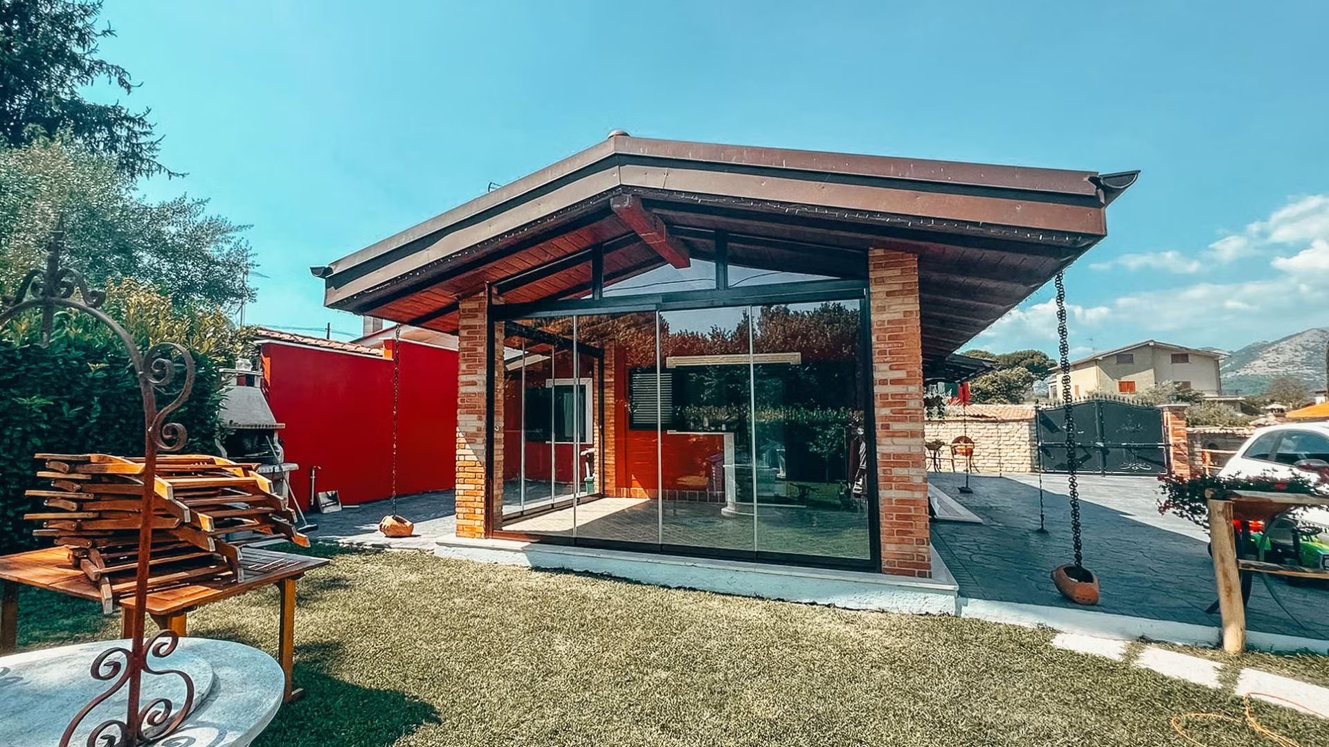 Una piccola casa con il tetto di legno e vetro si trova in mezzo a un rigoglioso campo verde.
