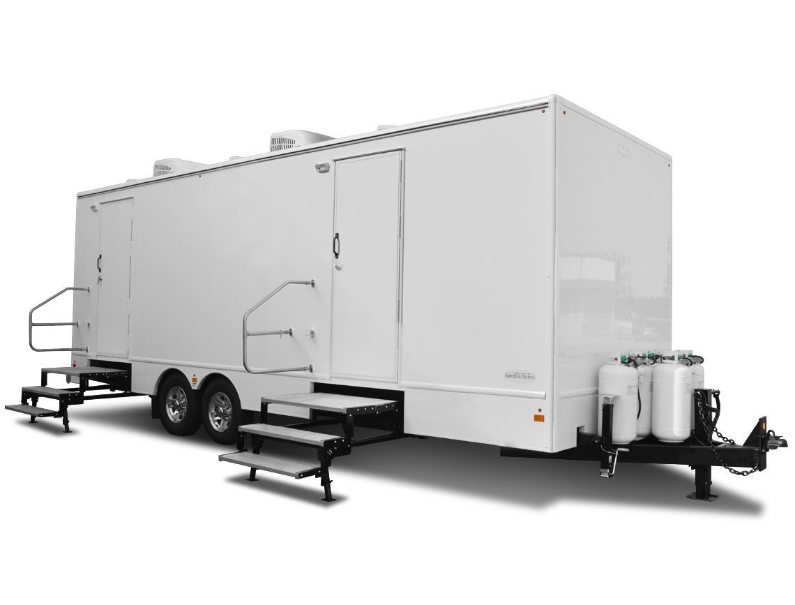 White, mobile restroom trailer with multiple doors, steps, and holding tanks on a trailer hitch.
