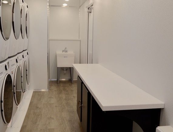 Laundry room interior with washers on the left, counter on the right, and a sink in the back.