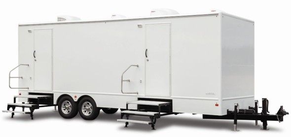 White dual-axle enclosed trailer with side doors and rear ramp stairs on a plain background