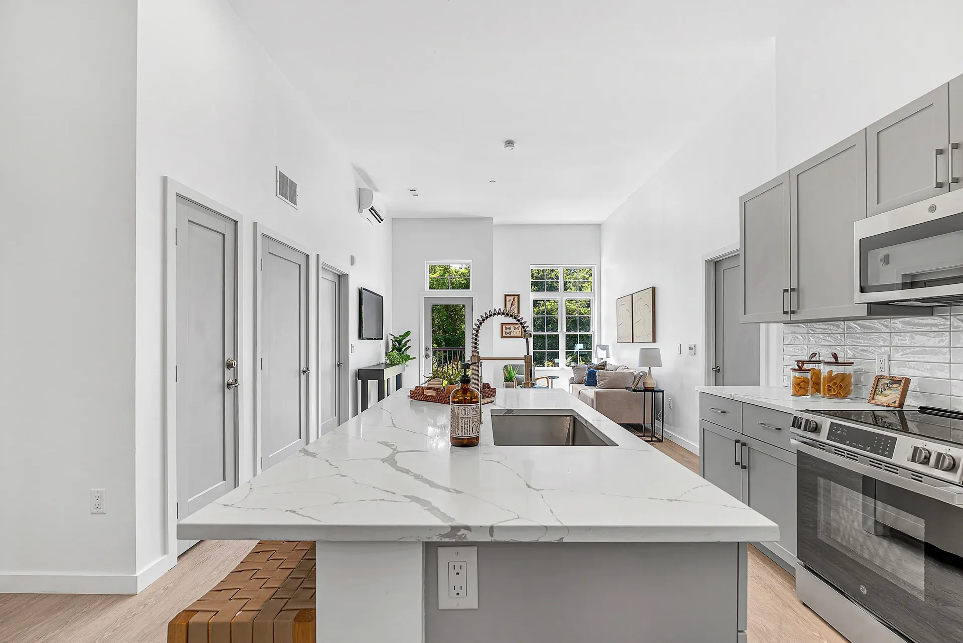 Modern kitchen island with sink and faucet, overlooking living area with couch and windows.