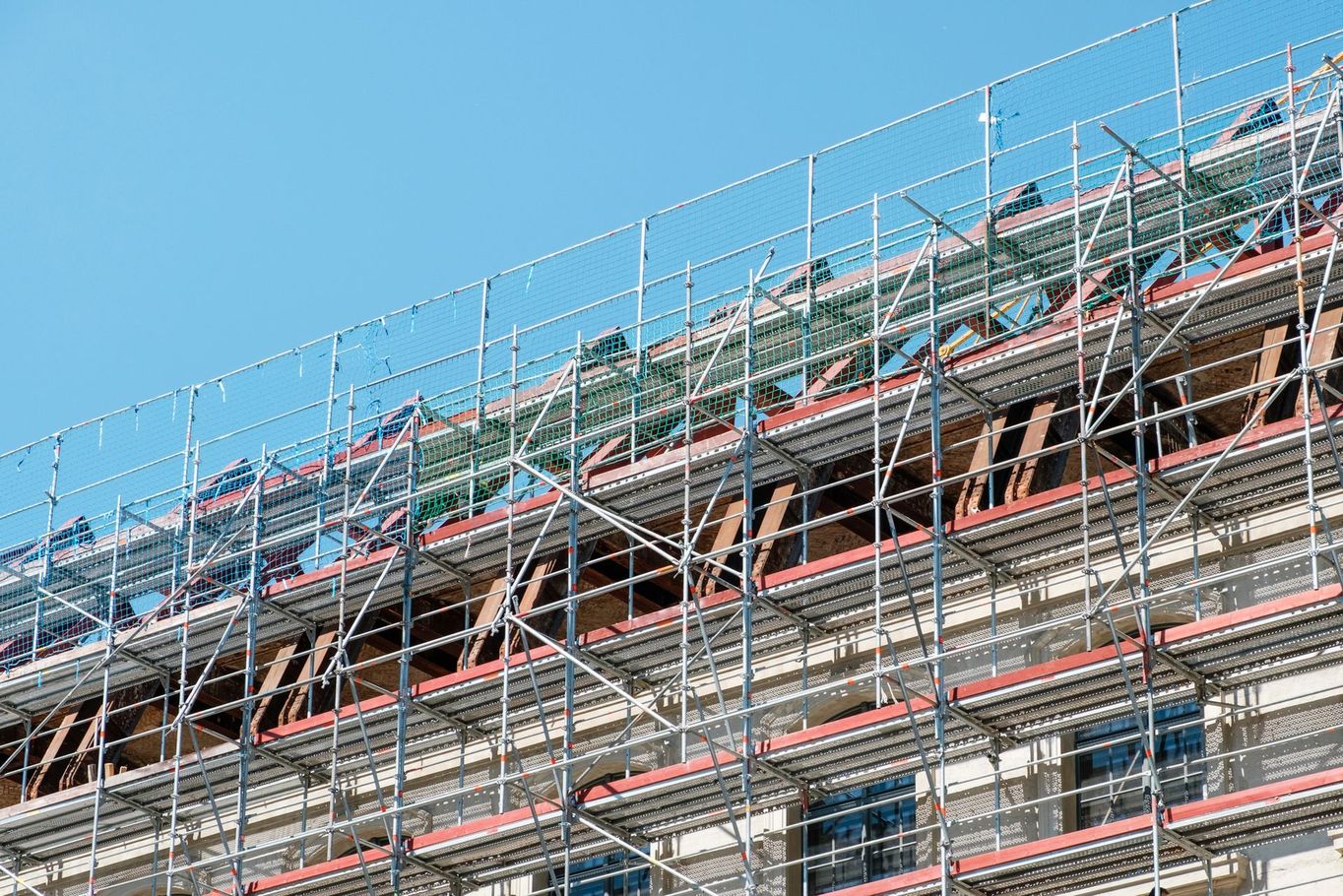 Impalcature che ricoprono la facciata di un edificio contro un cielo azzurro.