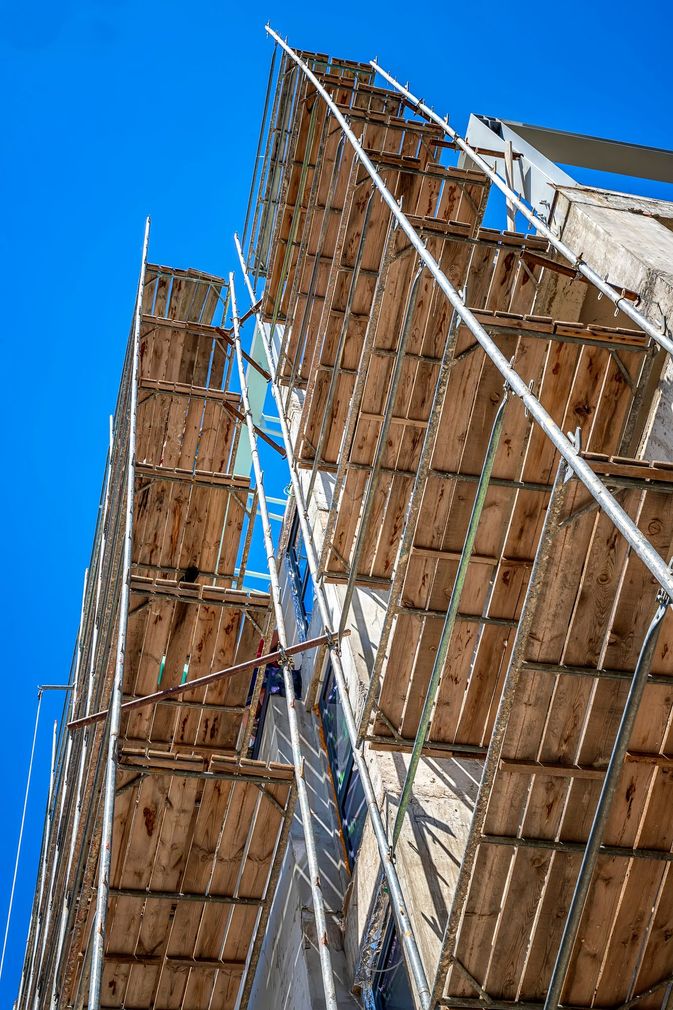 Alte impalcature con casseforme in legno contro un cielo azzurro brillante.