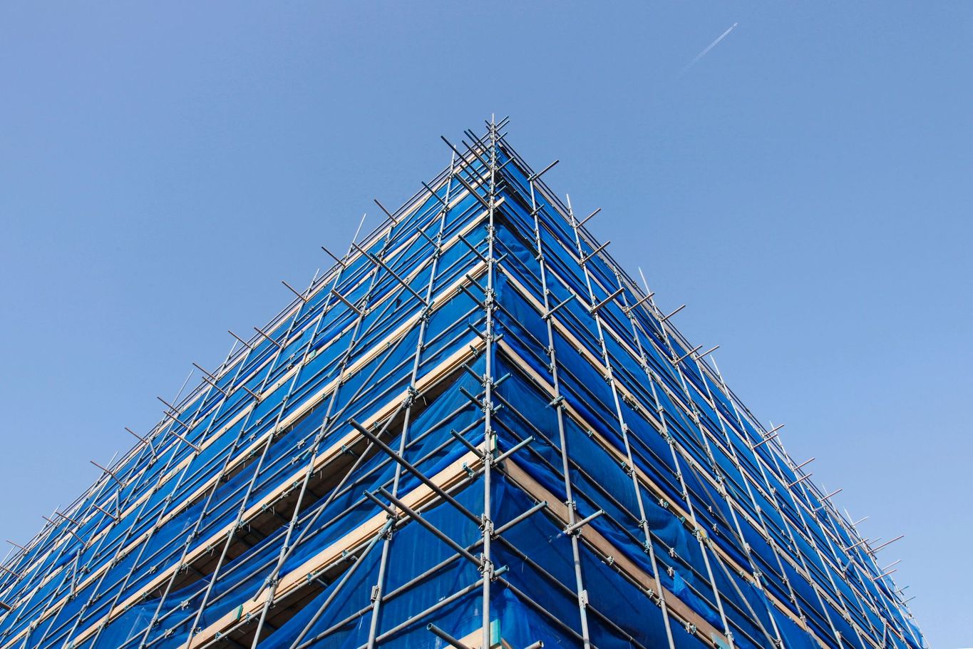 Impalcature blu da cantiere attorno a un edificio sullo sfondo di un cielo limpido.