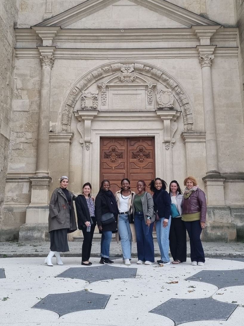 A group of women are posing for a picture in front of a building.