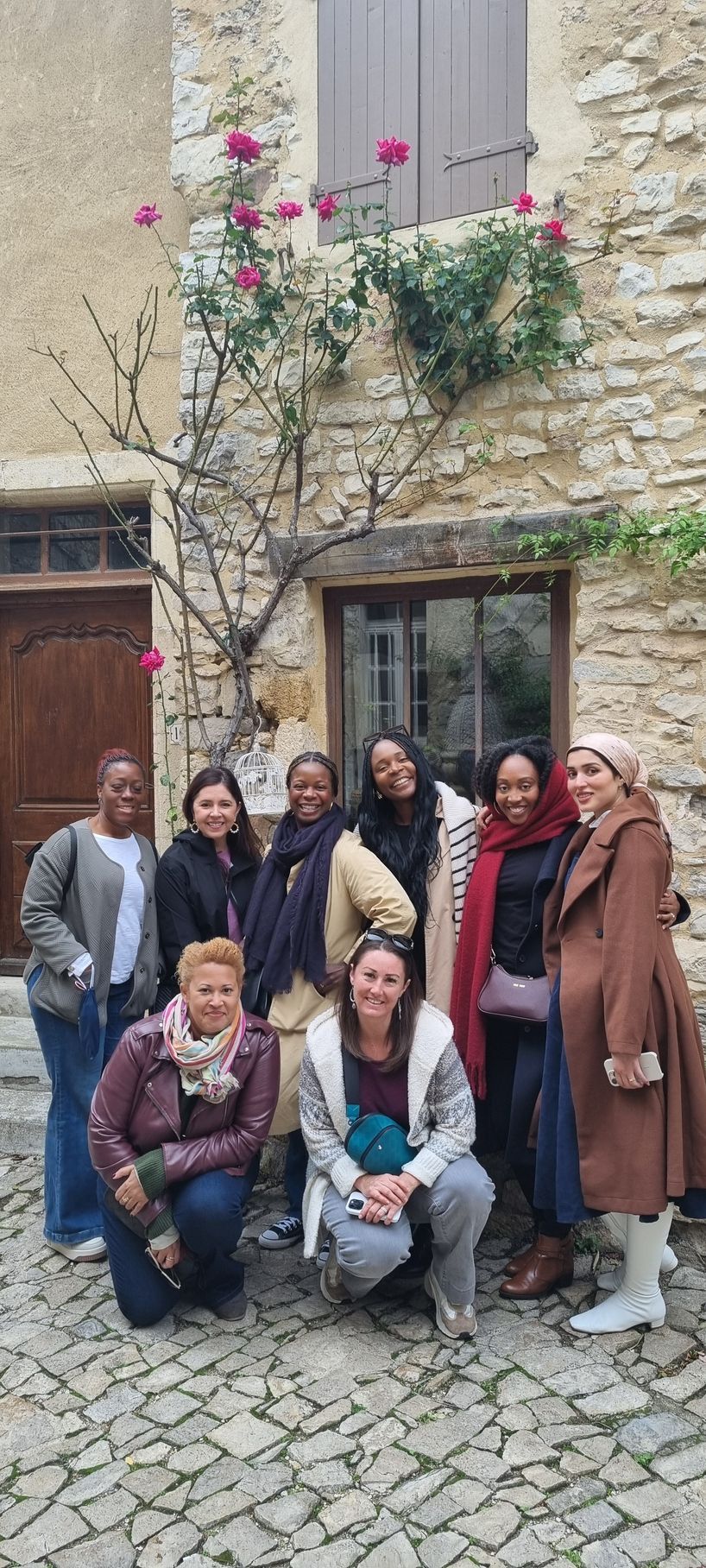 A group of women are posing for a picture in front of a stone building.