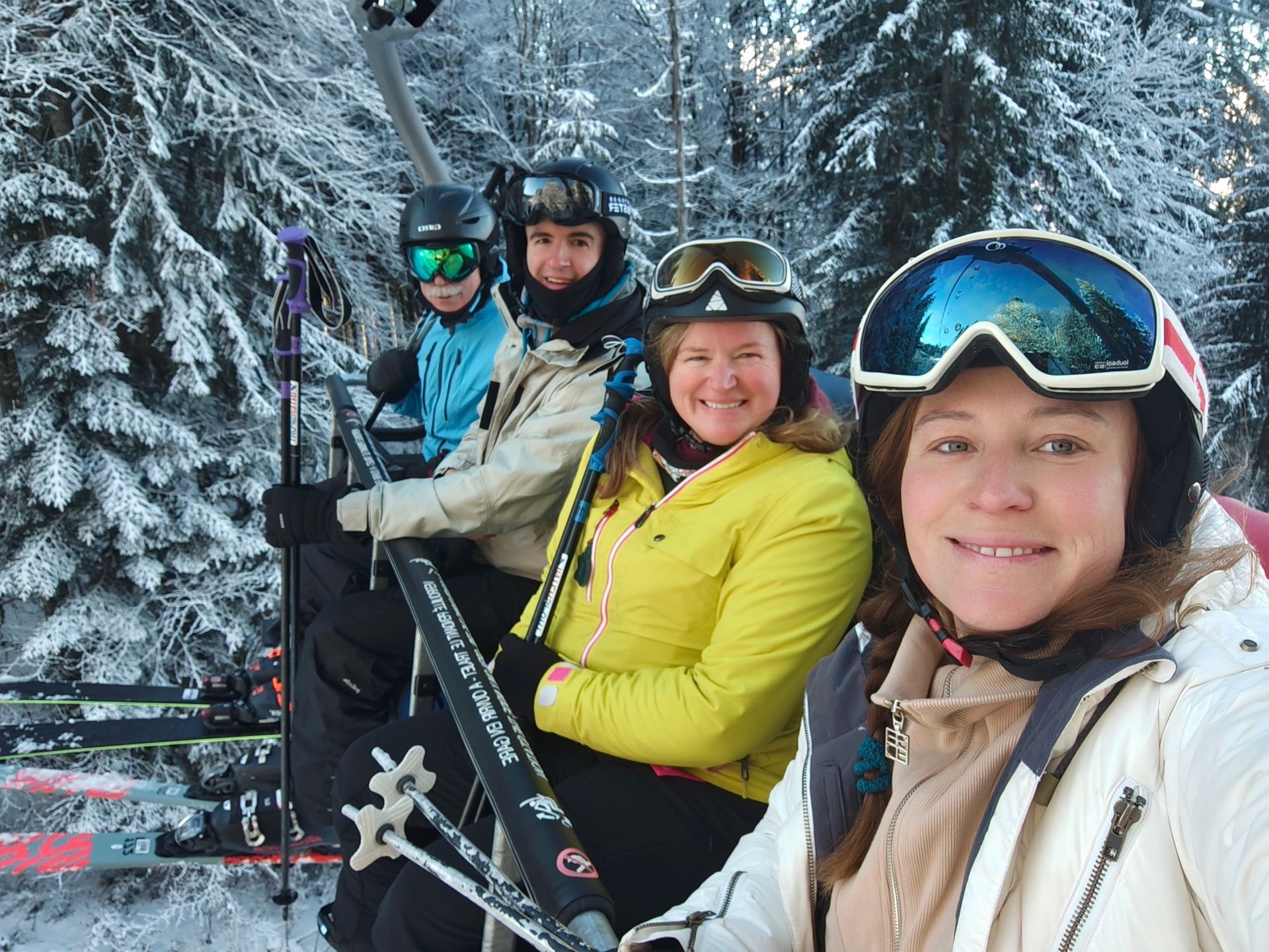 A group of people are sitting on a ski lift in the snow.
