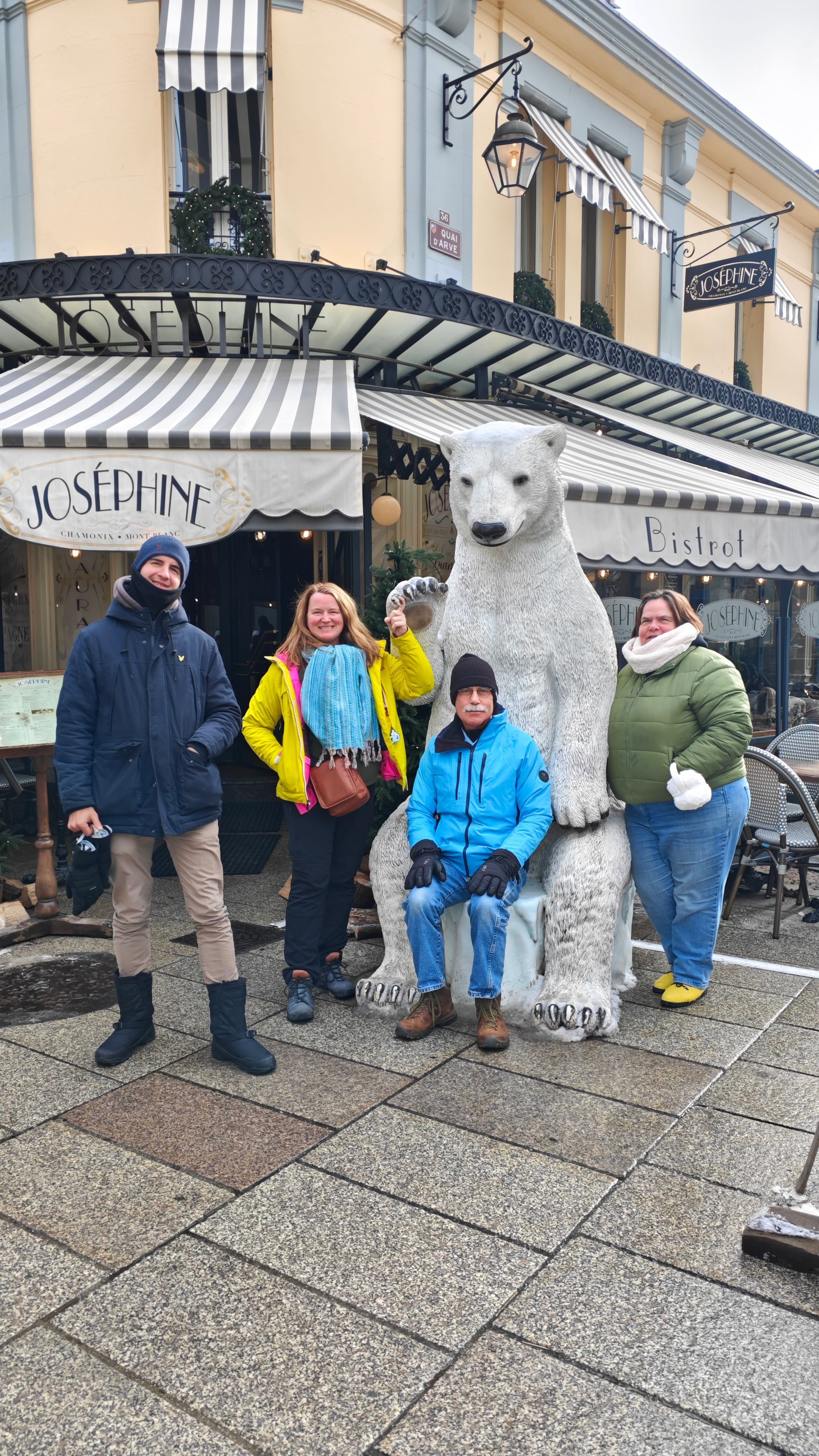 A group of people are posing for a picture in front of a polar bear statue.