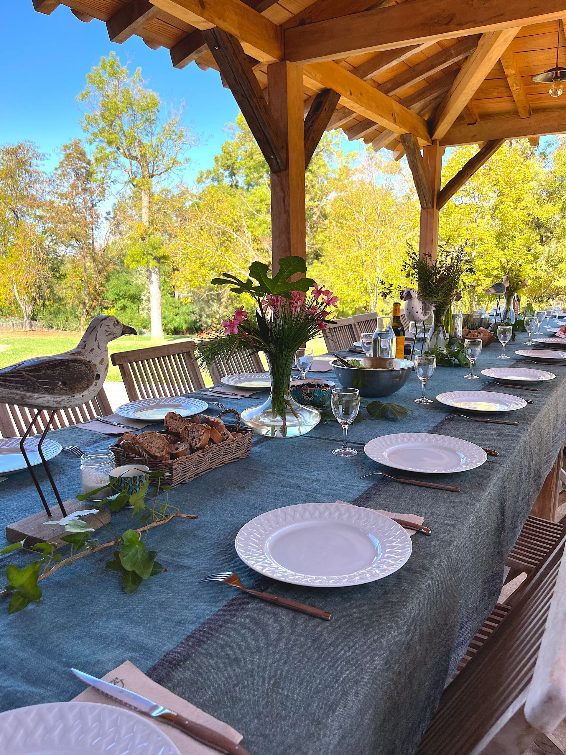 A long table with plates , utensils , and a bird on it.