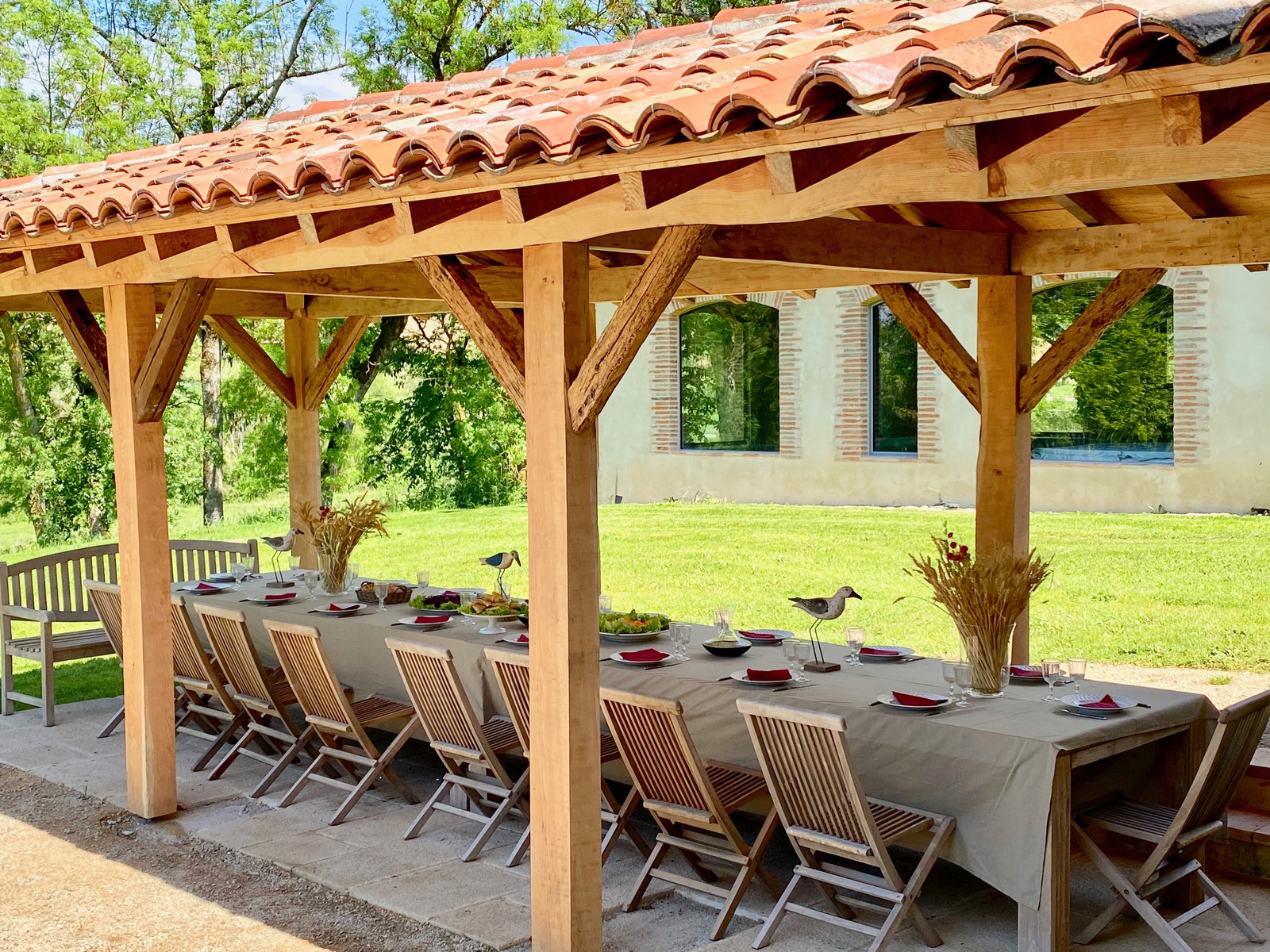 A long table and chairs under a wooden roof.