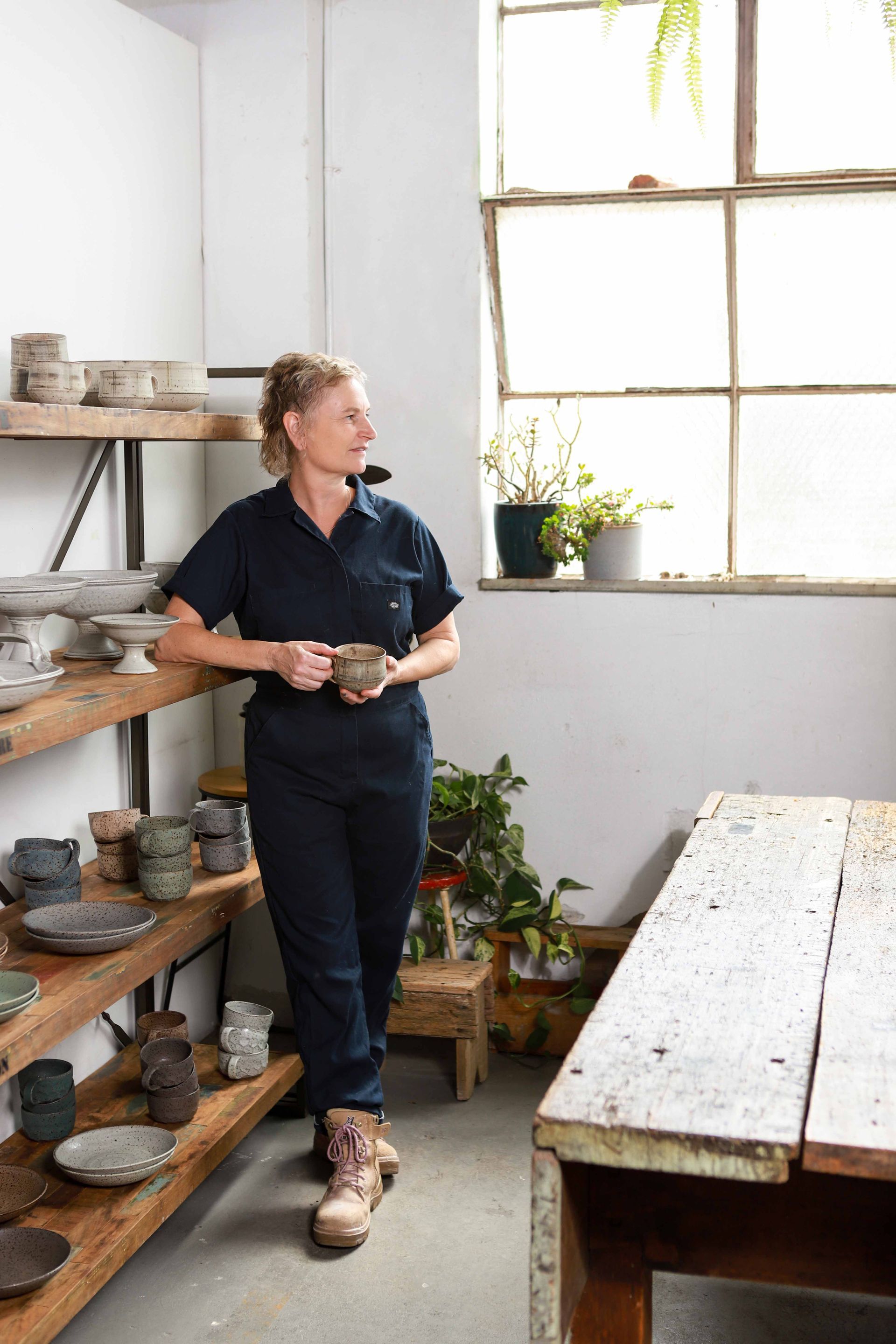 A woman is sitting on a pottery wheel making a bowl.