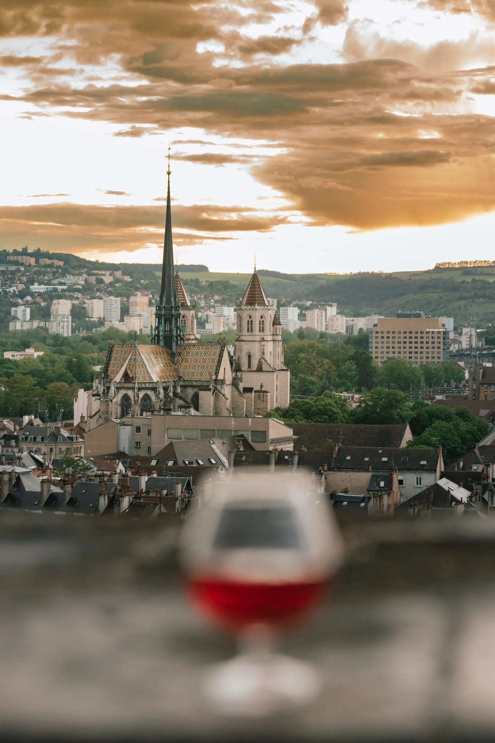 A wine glass with a view of a city in the background.