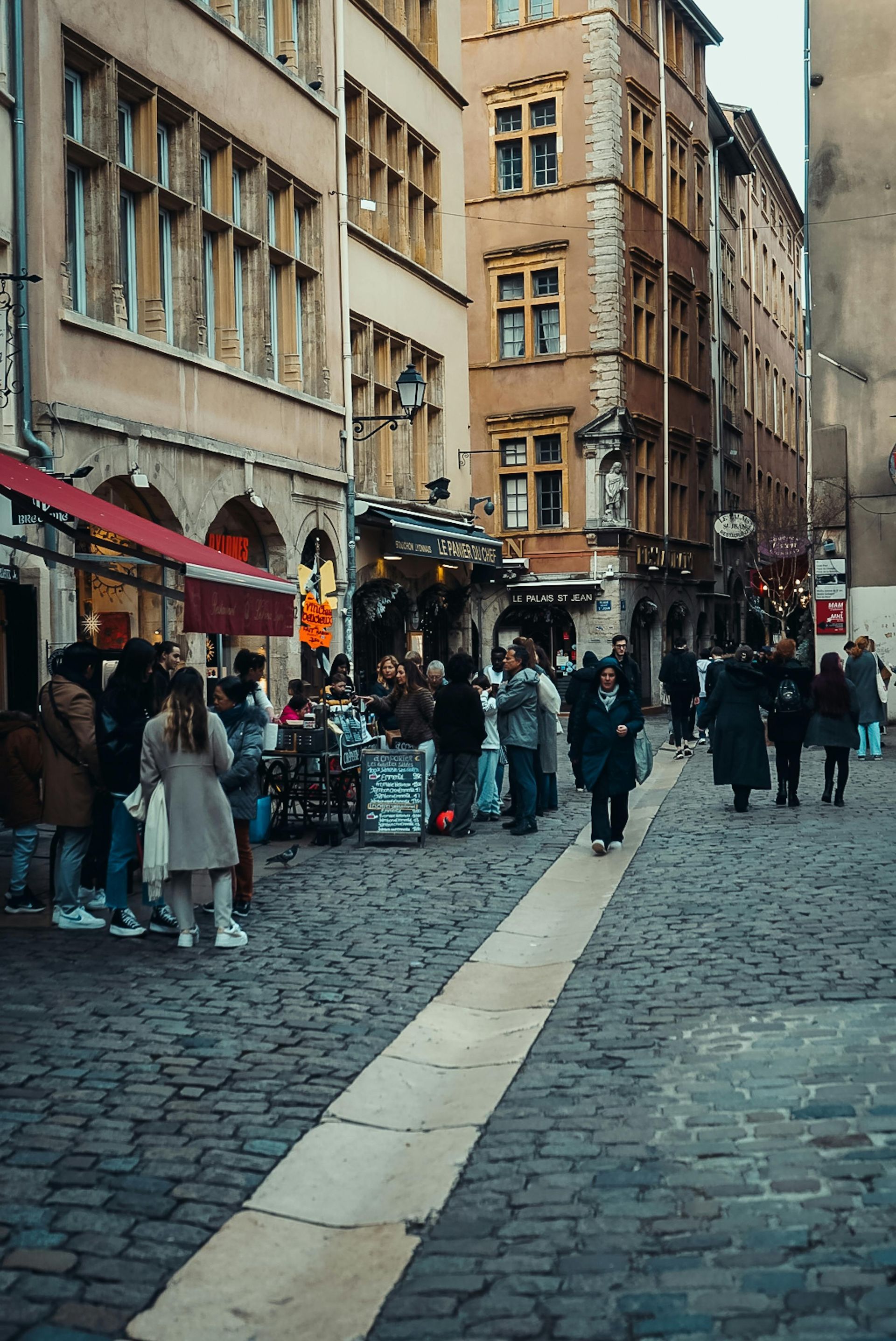 A group of people are walking down a cobblestone street in a city.