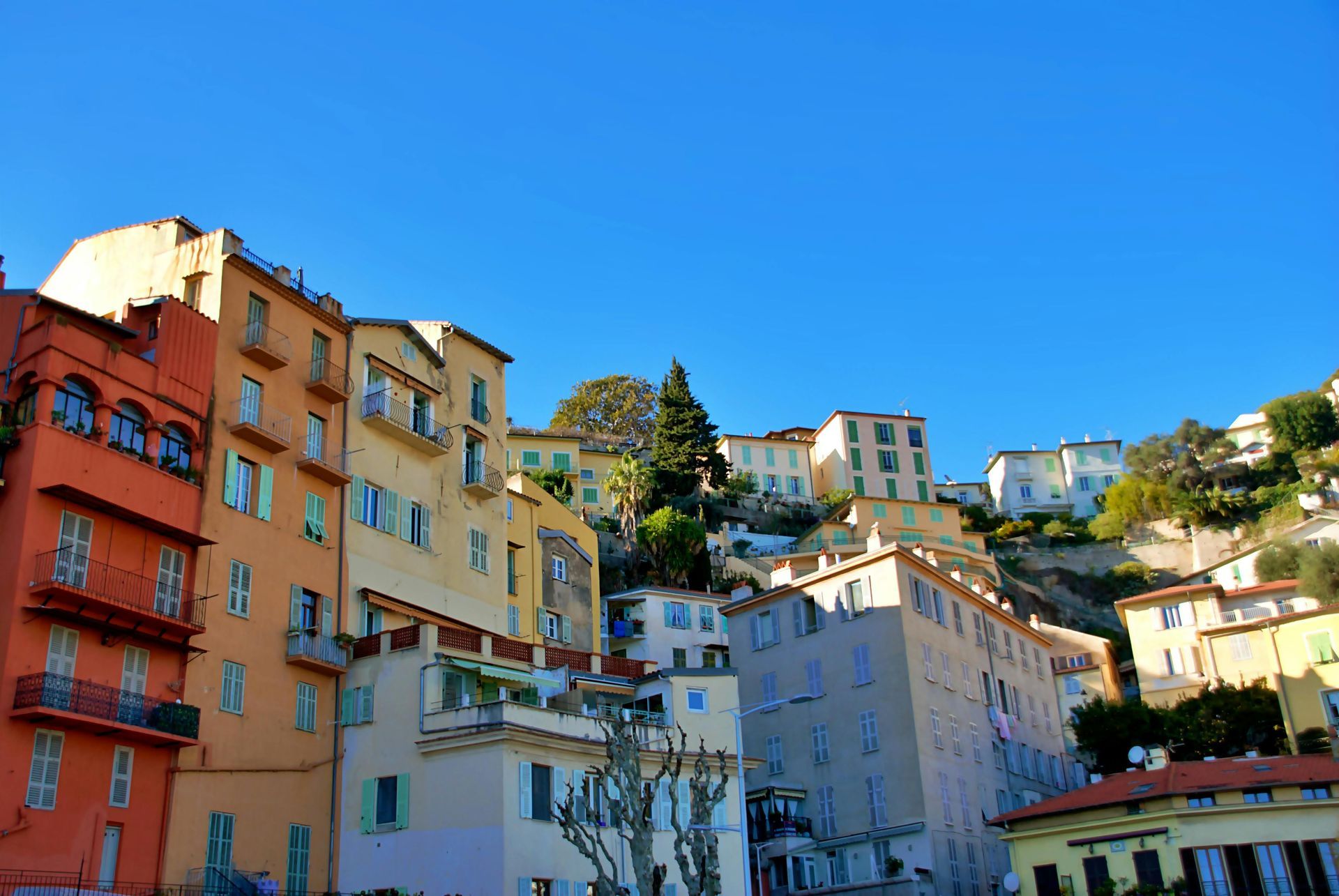 A row of buildings on a hillside with a blue sky in the background