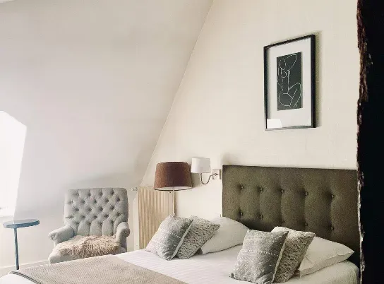 A bedroom with a bed , chair , lamp and picture on the wall.