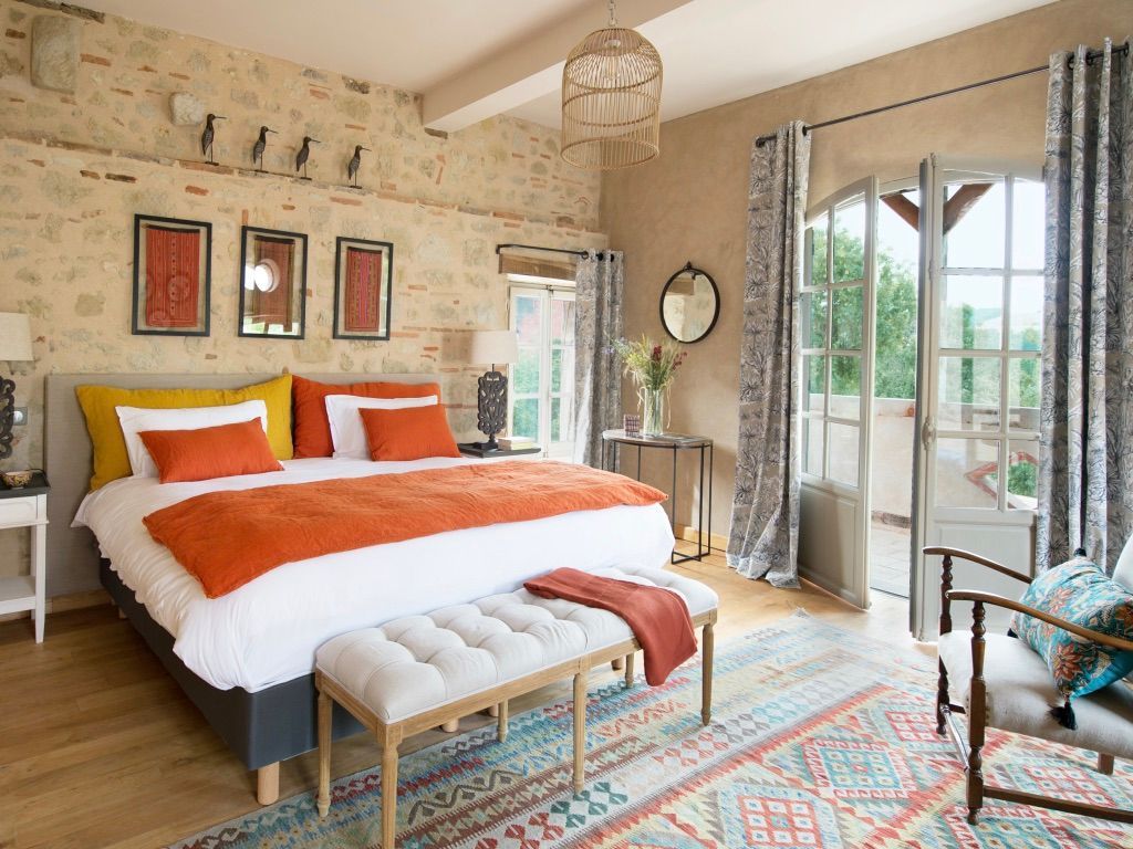 A bedroom with a large bed , bench , chair and window.