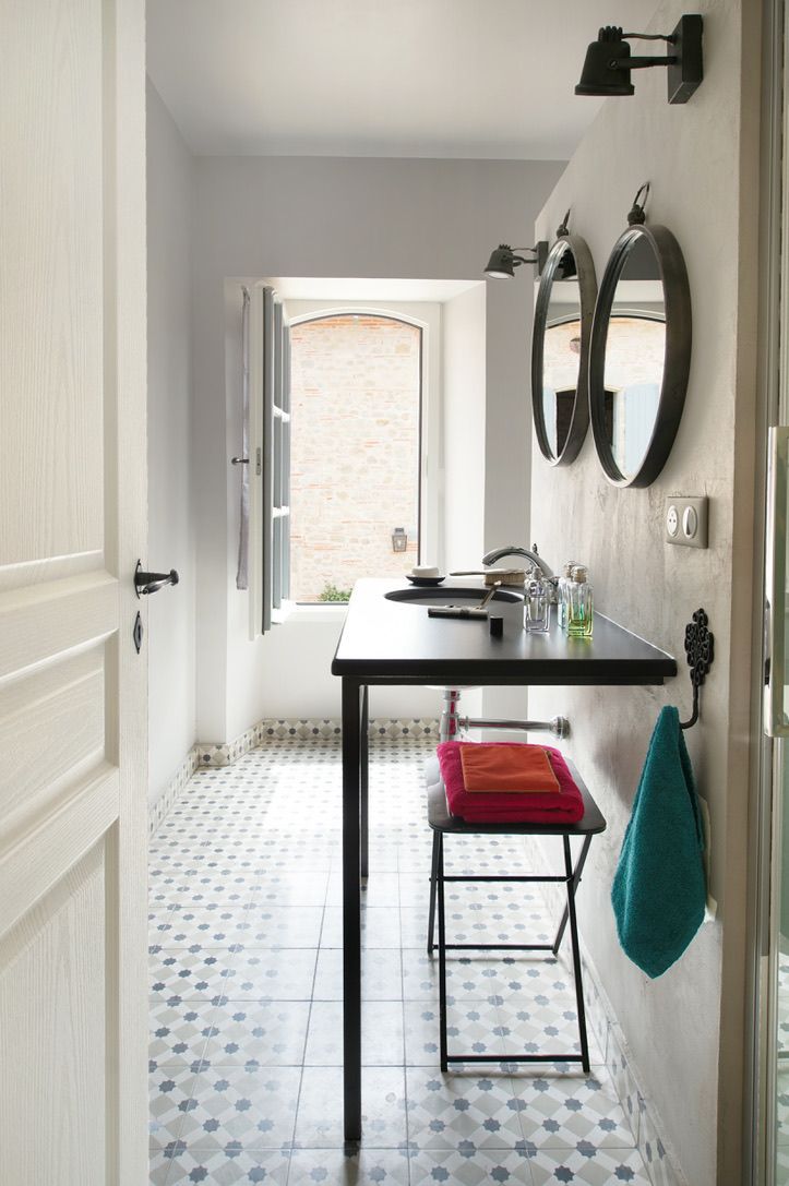 A hallway with a table and two mirrors on the wall