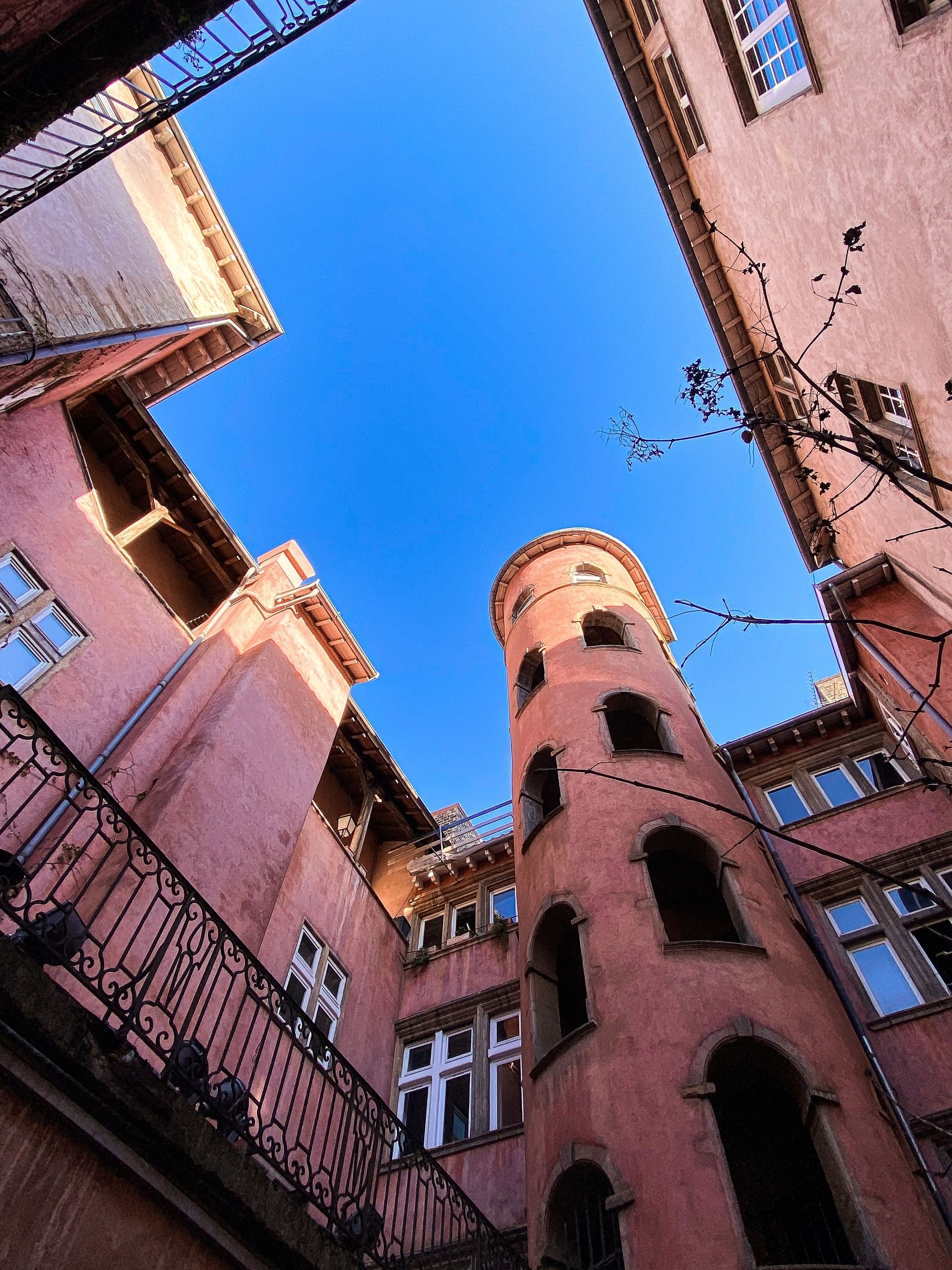 Looking up at a tower between two pink buildings.
