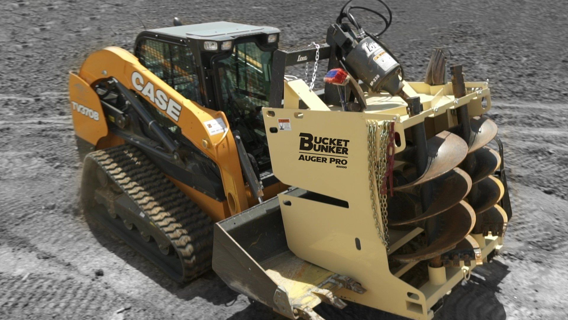 A case track loader is driving through a dirt field with a fully loaded bucket bunker attached to the front bucket.