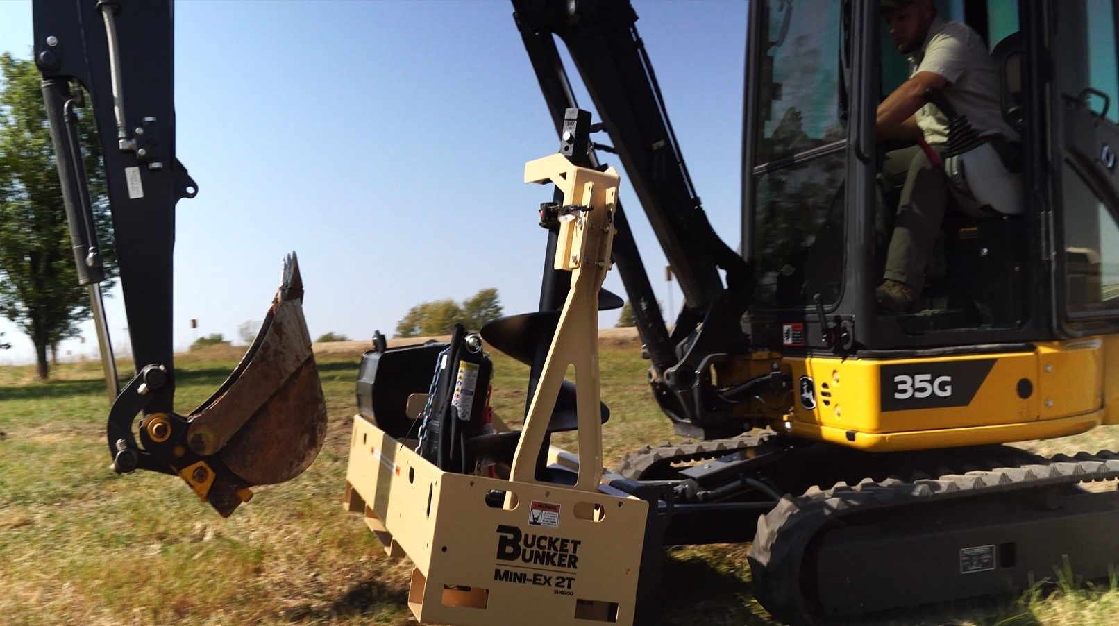 Mini-excavator with a Bucket Bunker® Mini-EX 2T mounted to it's front blade, hauling attachments around the job site.
