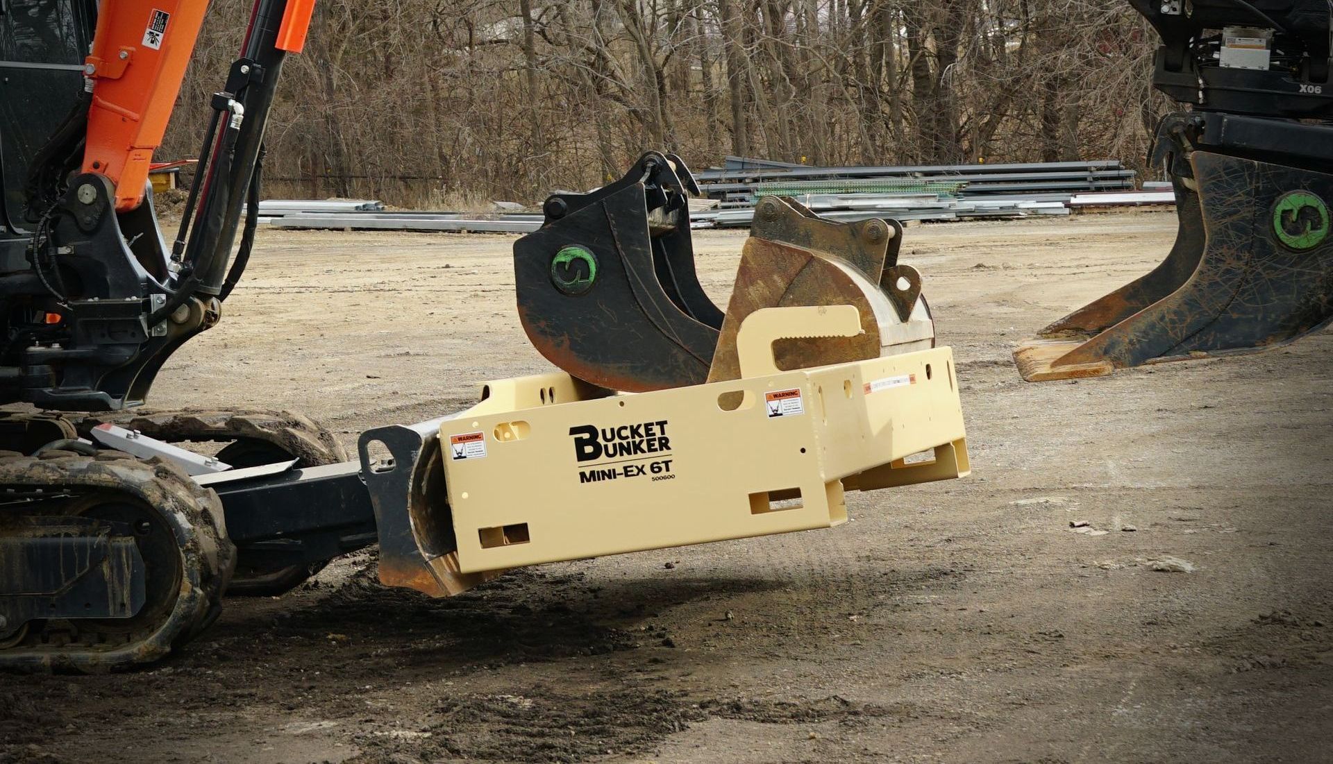 Mini-excavator with a Bucket Bunker® Mini-EX 6Tmounted to it's front blade, hauling attachments around the job site.