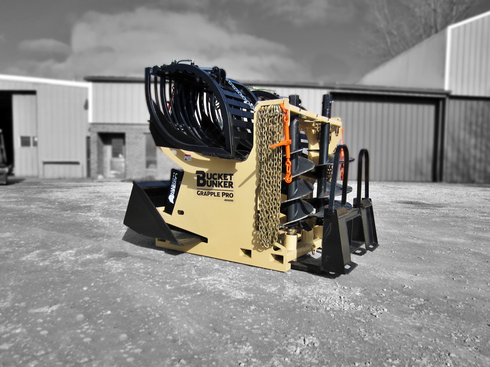 A Bucket Bunker loaded with skid steer attachments, grapple bucket, auger drive, auger bits, loader bucket, and pallet forks.