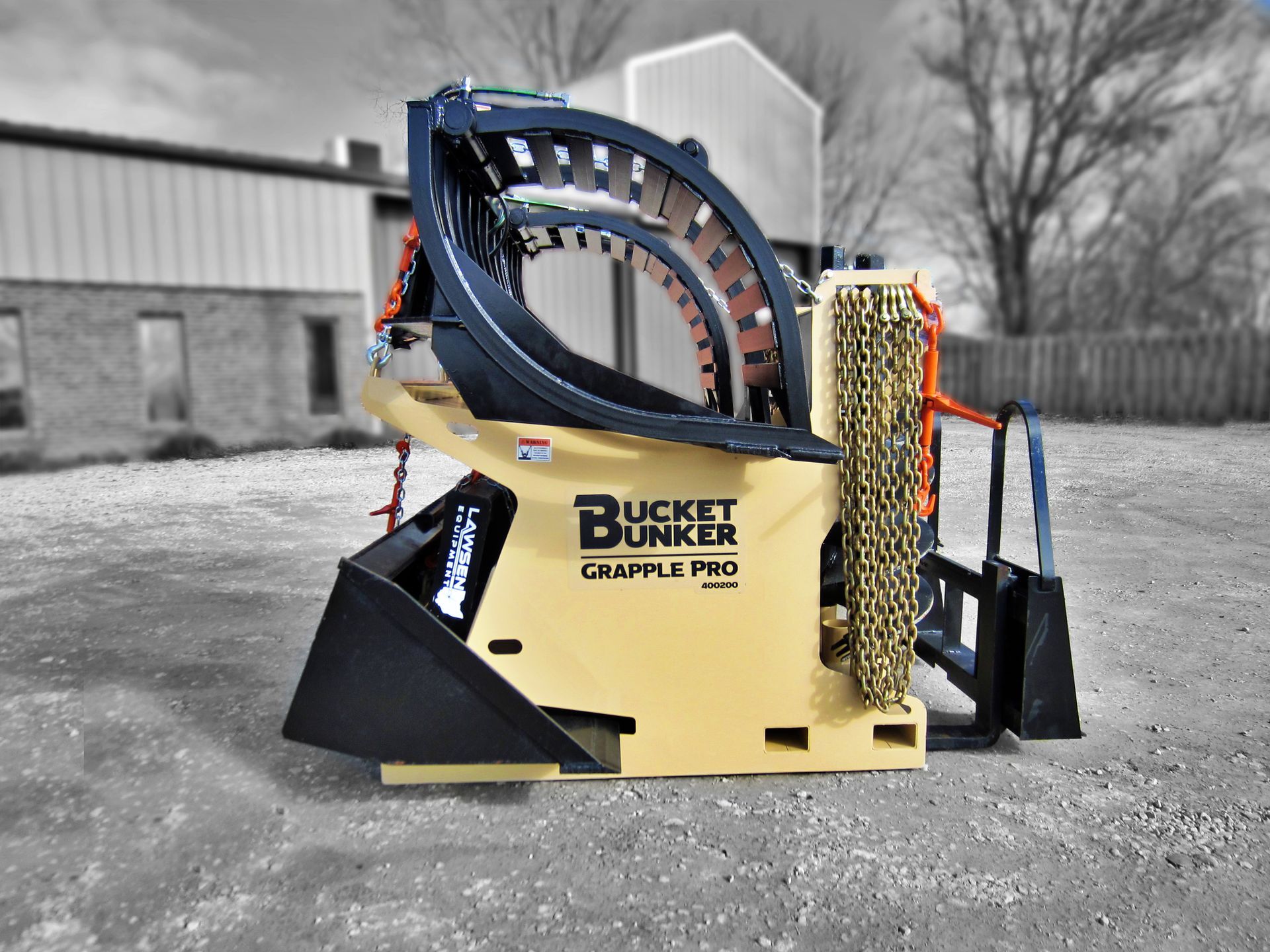 A Bucket Bunker loaded with skid steer attachments, grapple bucket, auger drive, auger bits, loader bucket, and pallet forks.