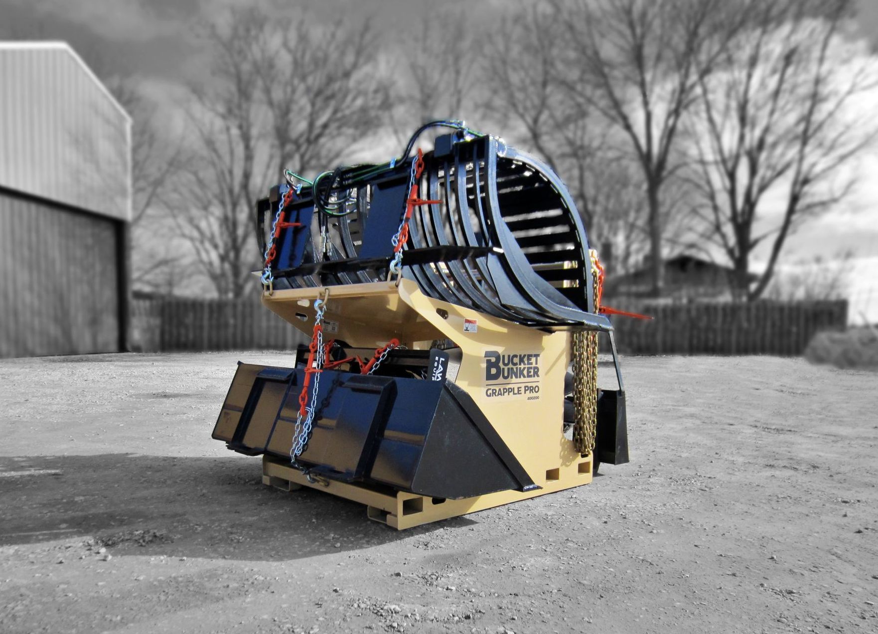 Bucket Bunker fully loaded with skid steer attachments including grapple bucket, loader bucket, and pallet forks. 