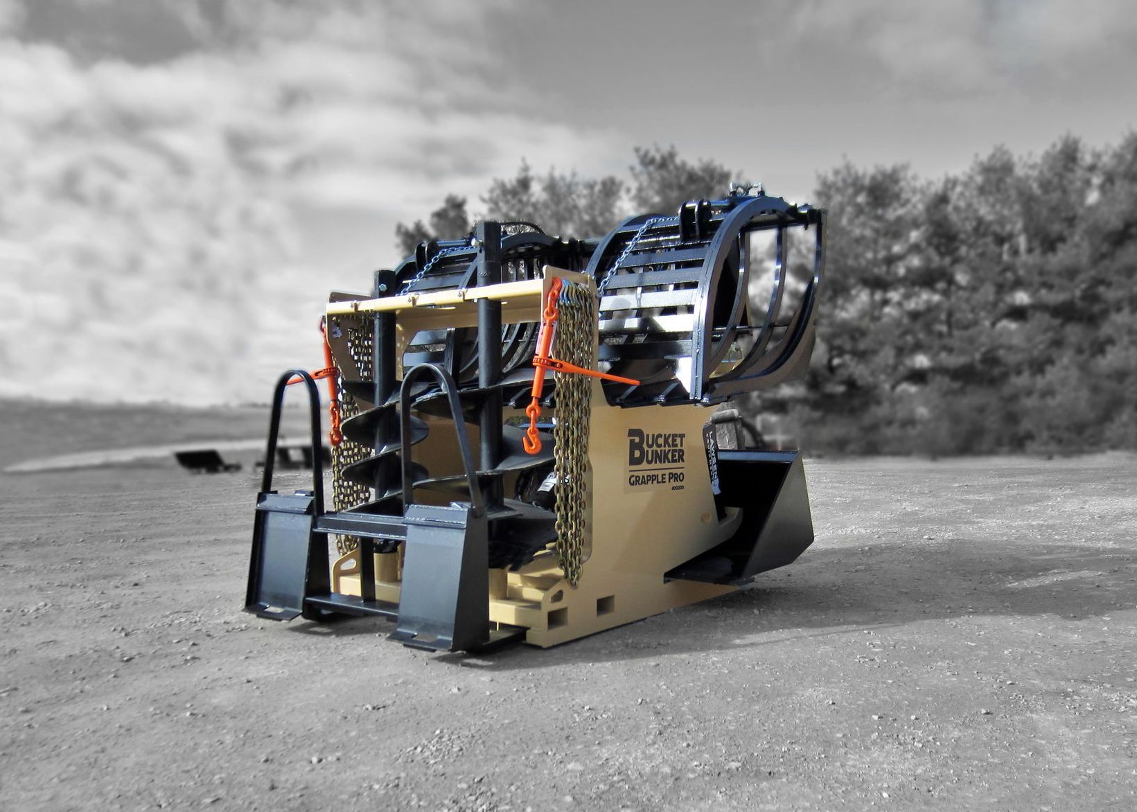 A Bucket Bunker loaded with skid steer attachments, grapple bucket, auger drive, auger bits, loader bucket, and pallet forks.