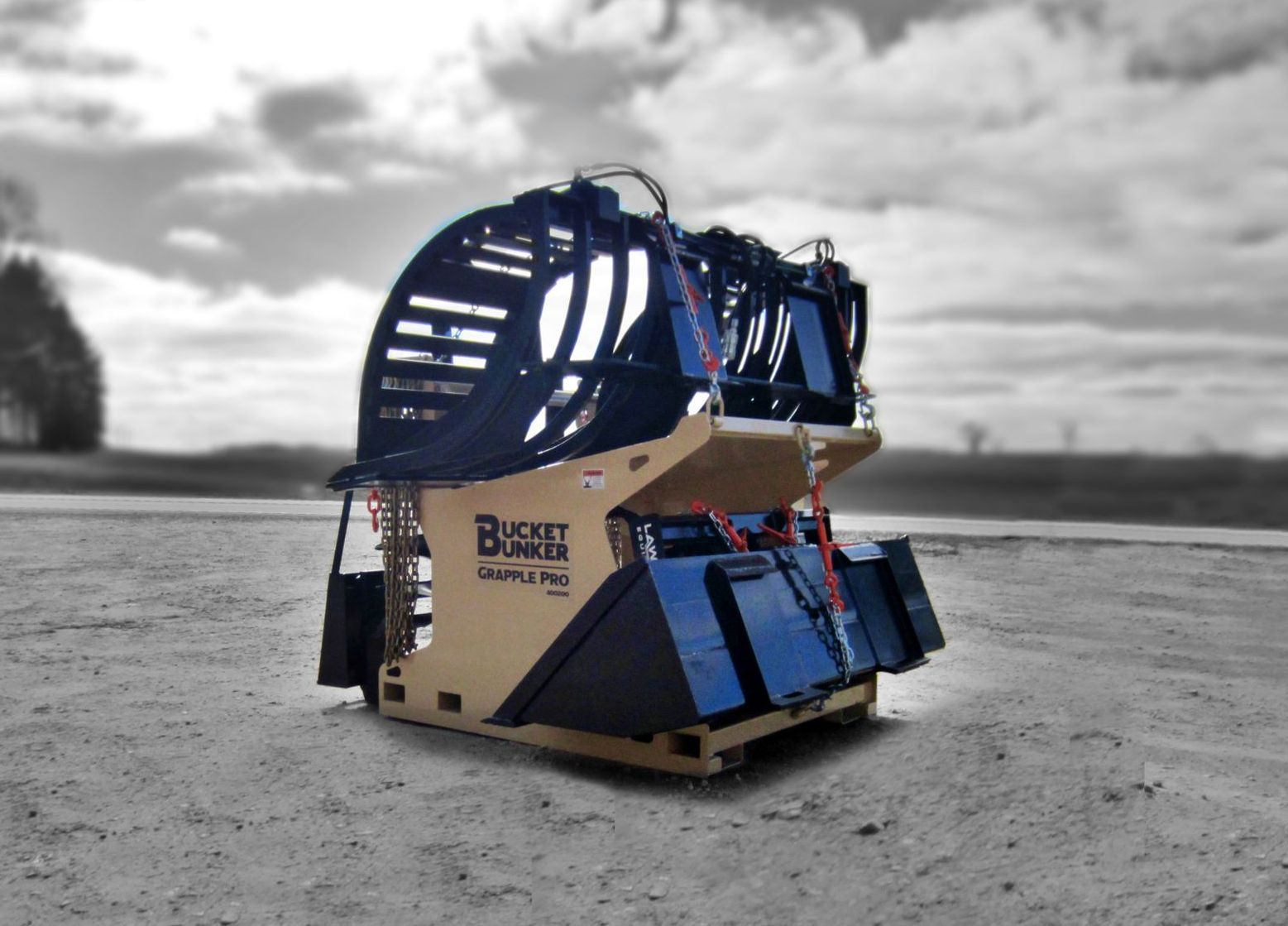 A Bucket Bunker loaded with skid steer attachments, grapple bucket, auger drive, auger bits, loader bucket, and pallet forks.