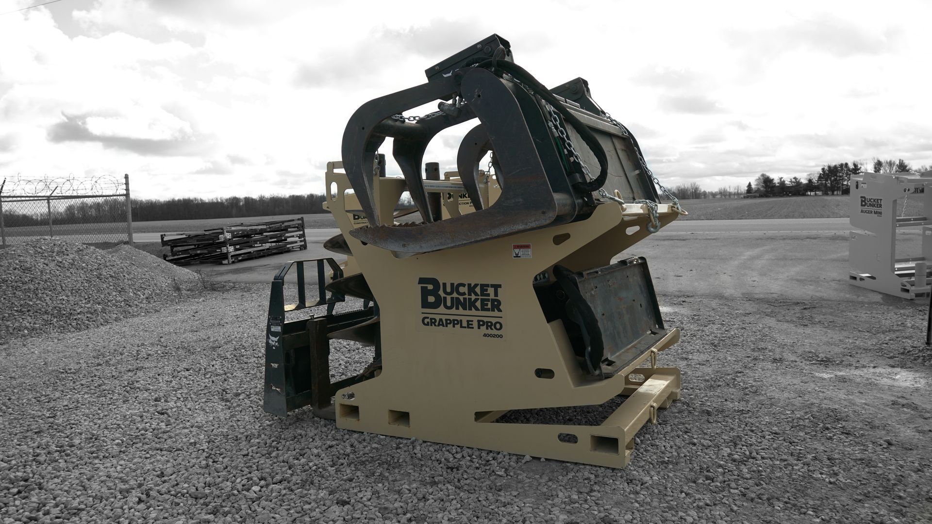 Bucket Bunker fully loaded with skid steer attachments including grapple bucket, auger drive, and auger bits.