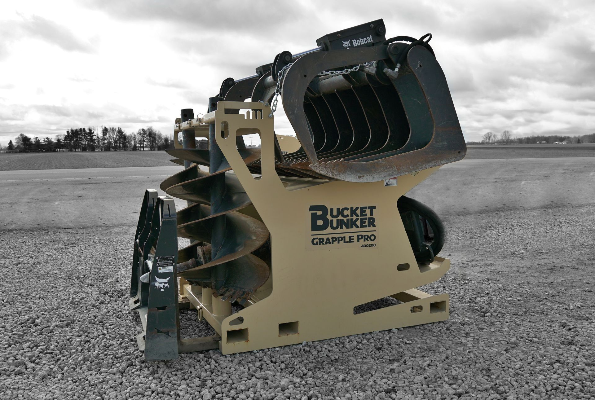Bucket Bunker fully loaded with skid steer attachments including grapple bucket, auger drive, and auger bits.